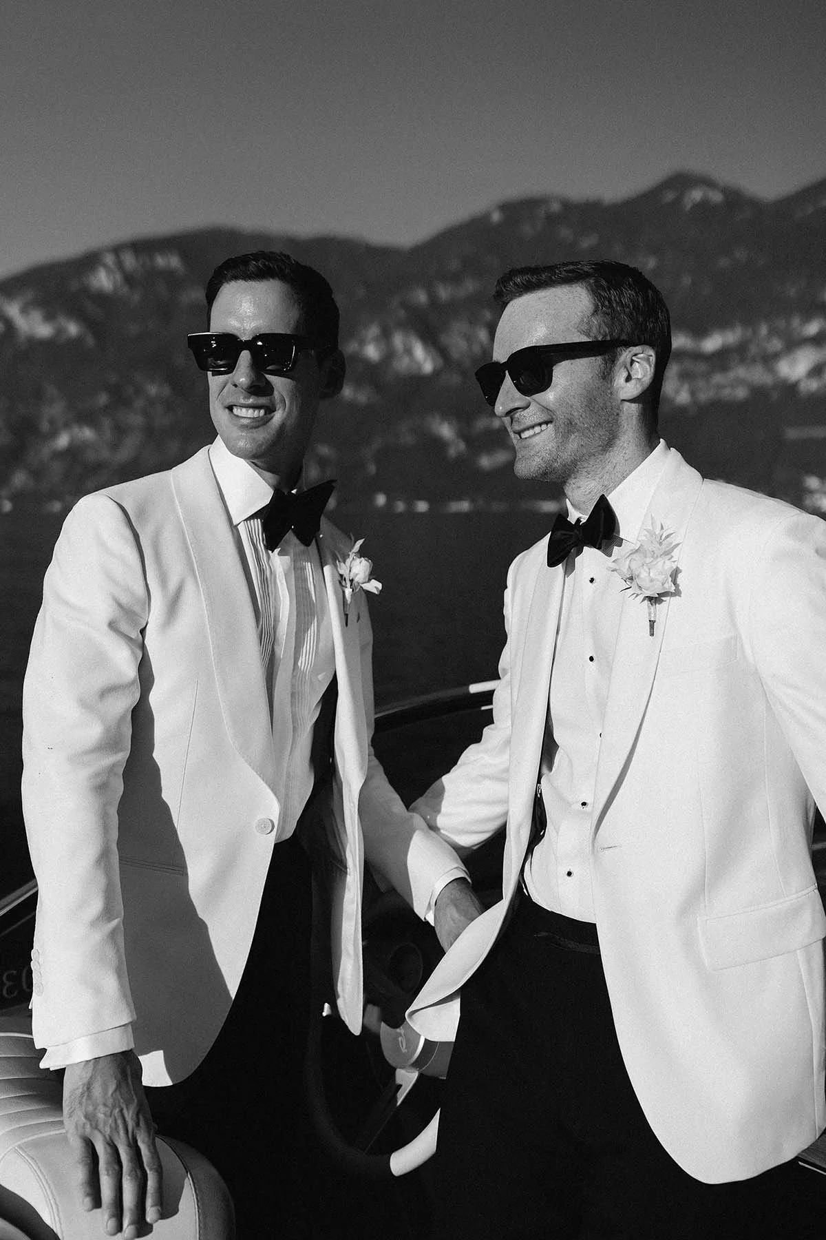 two grooms looking into sunset on a boat in Lake Como
