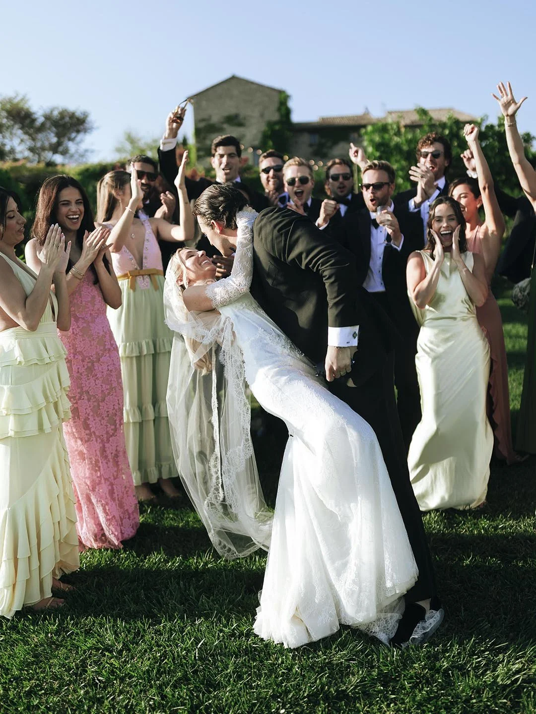bride and groom kiss each other with their guests celebrating with Castello di Petrata in the background