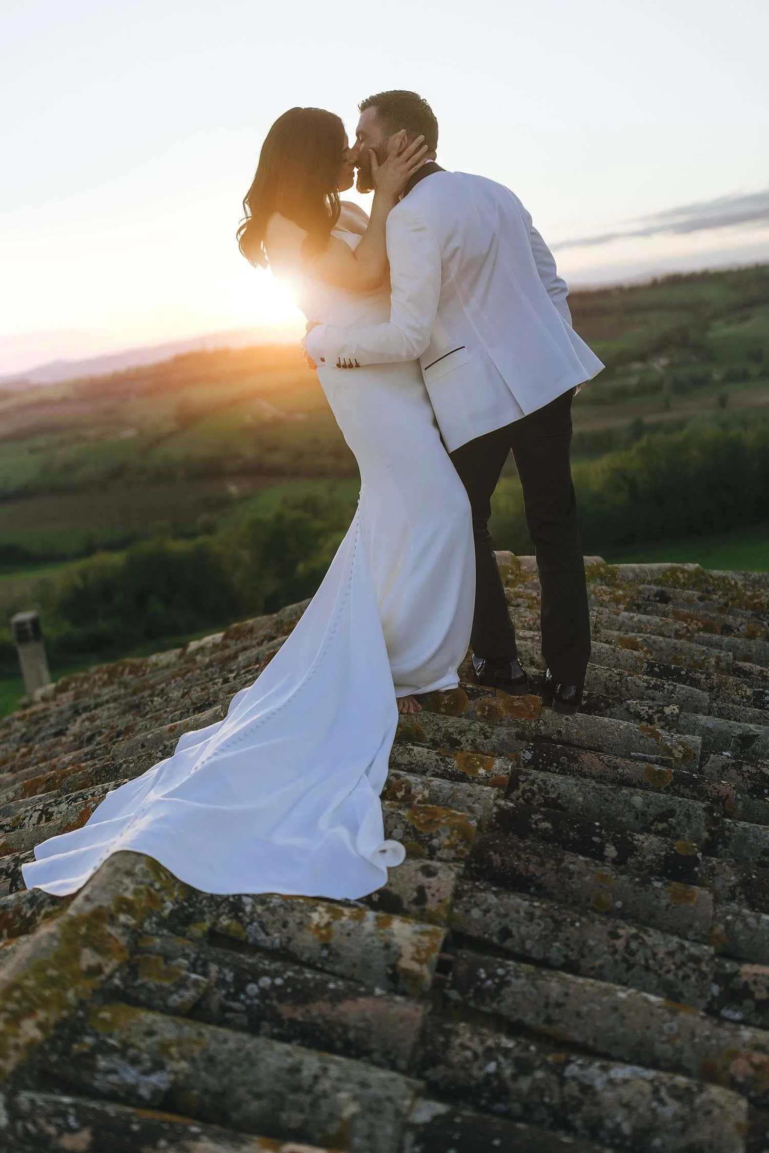 Groom and bride kissing on the roof of Castello di Montignano in Umbria at sunset. photo by Rellini art studio best wedding photographer in Umbria