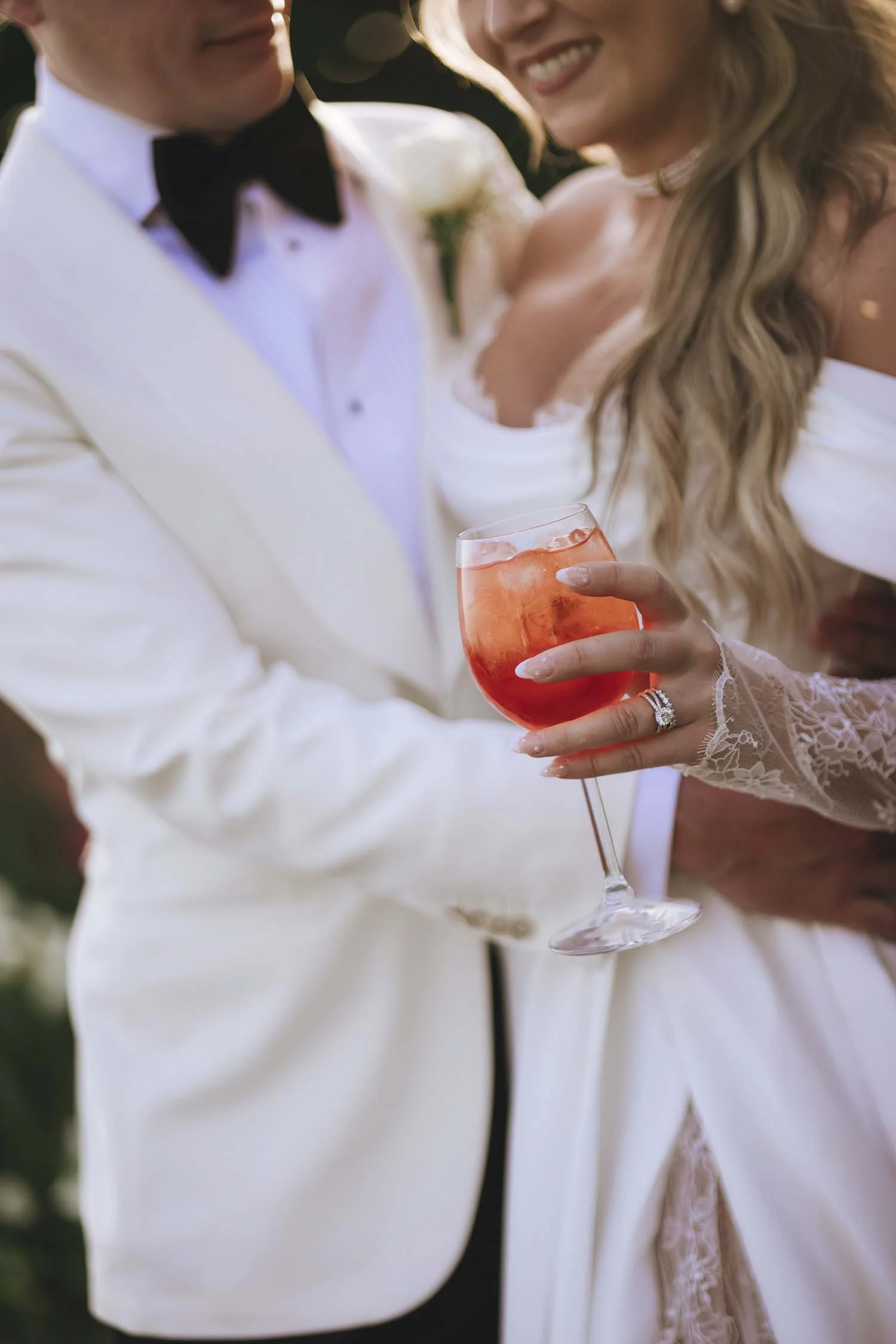 groom and bride holding each other while drinking aperol spritz