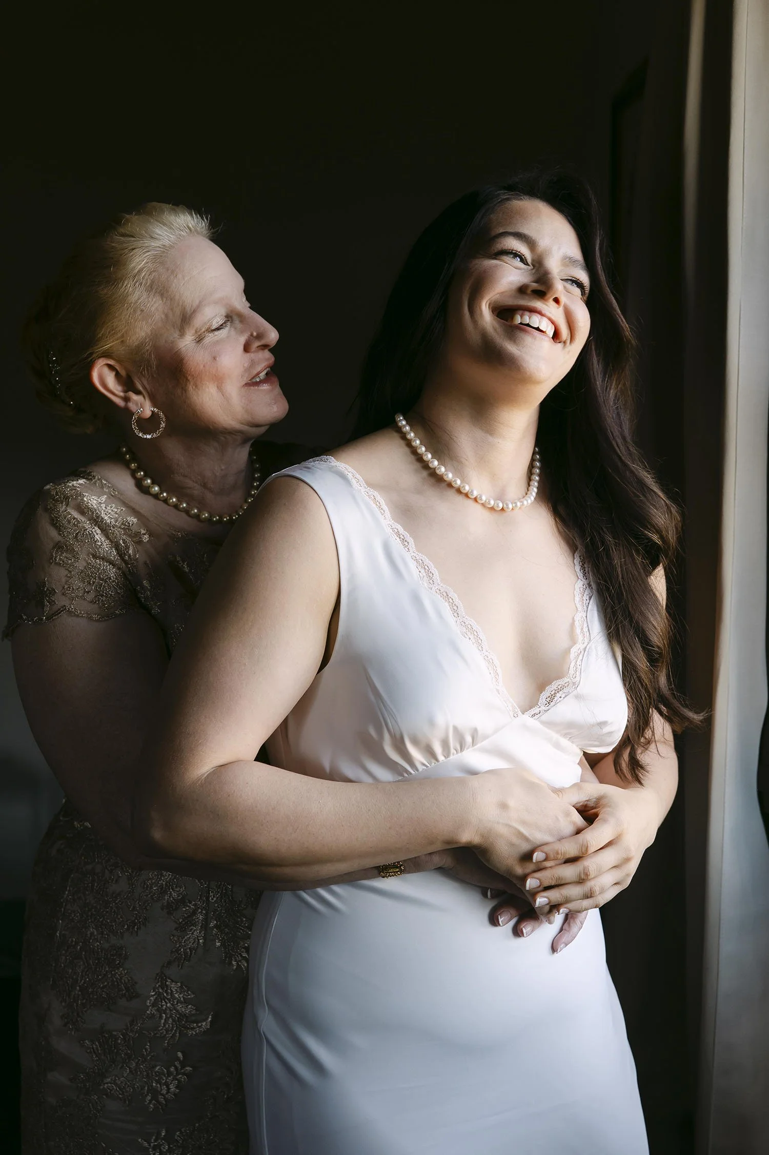 Bride hug by her mother by the window on the wedding day