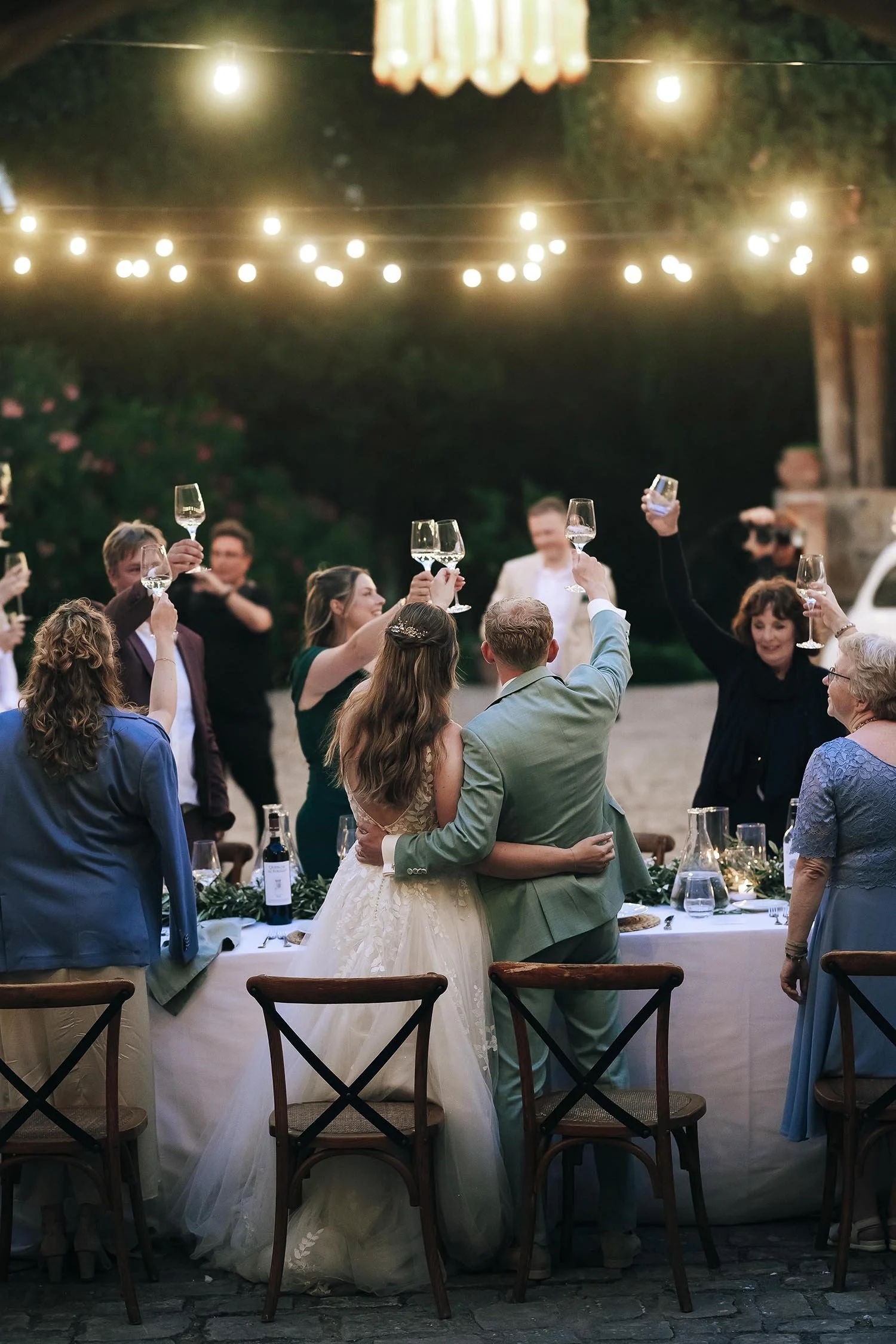 Bride and groom cheer with wine to their guests at the dinner table
