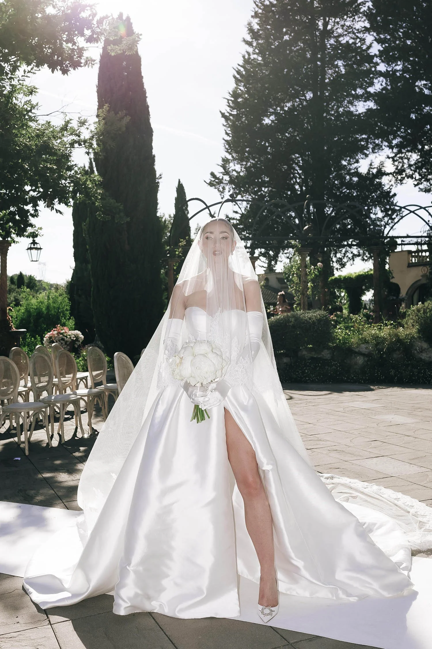the bride looking at the camera holding the flowers under the veil
