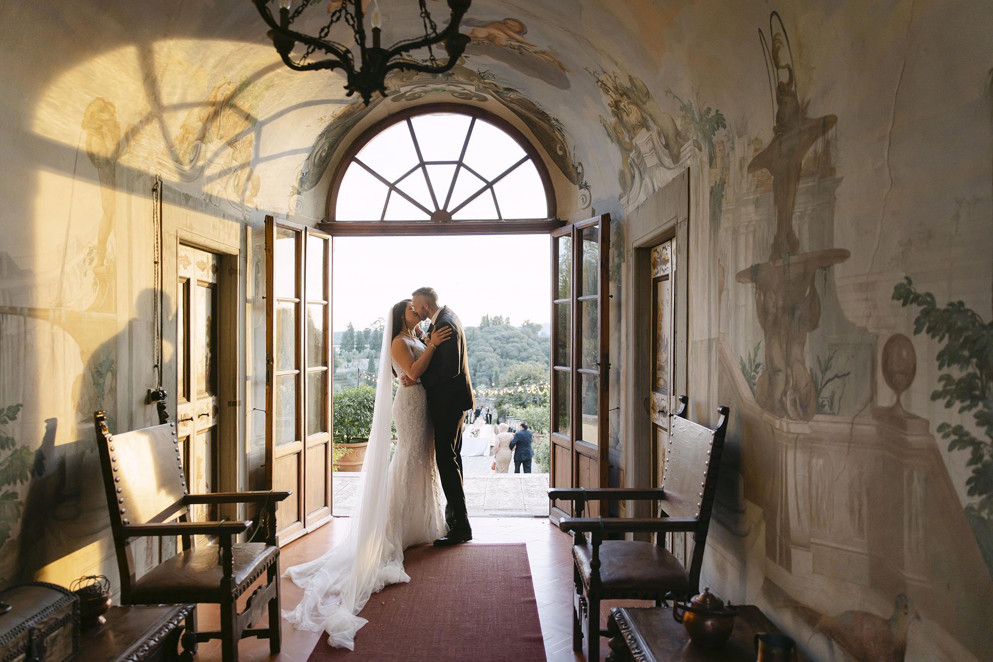 Kiss of the bride and groom in the gallery at Villa Medicea di Lilliano with the golden light of the sunset