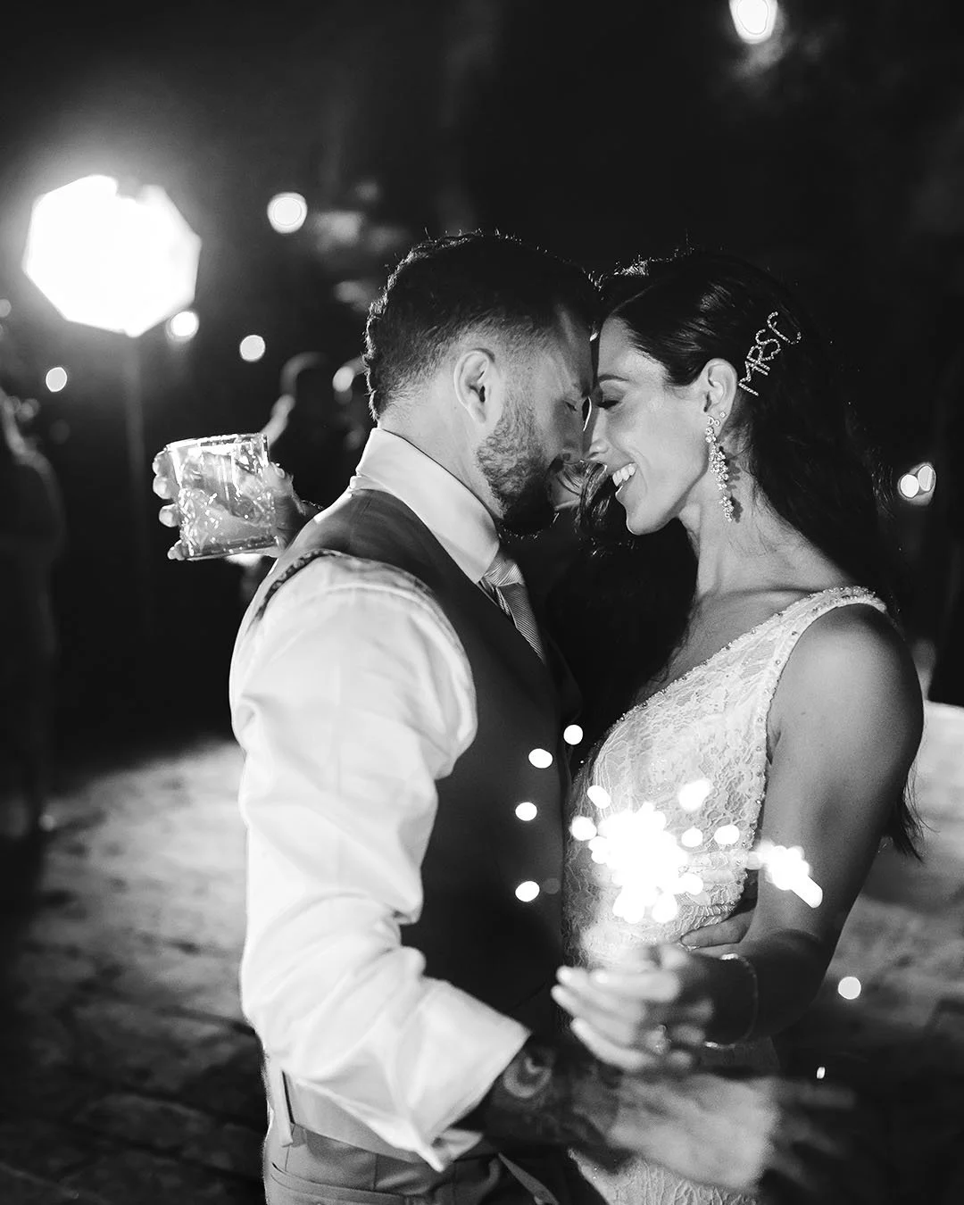 Bride and groom dancing together holding sparklers and drinks after their wedding at Borgo Stomennano