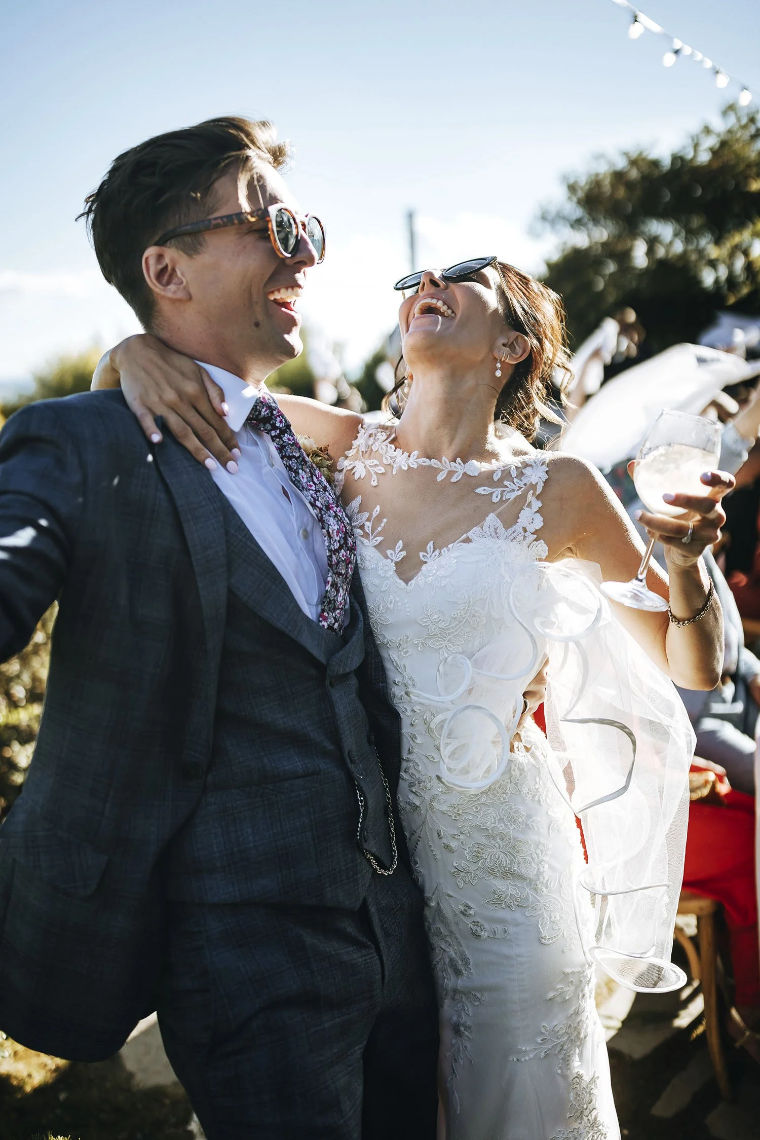 Bride and groom laughing together and holding each other celebrated by their guests seated at the dinner tables