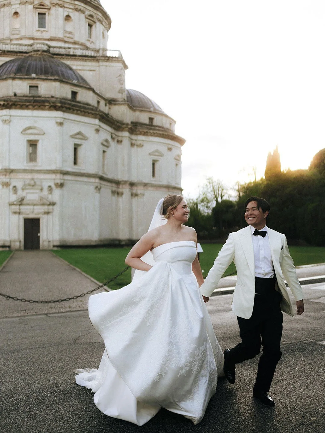 bride and groom cross the street with a church in the background