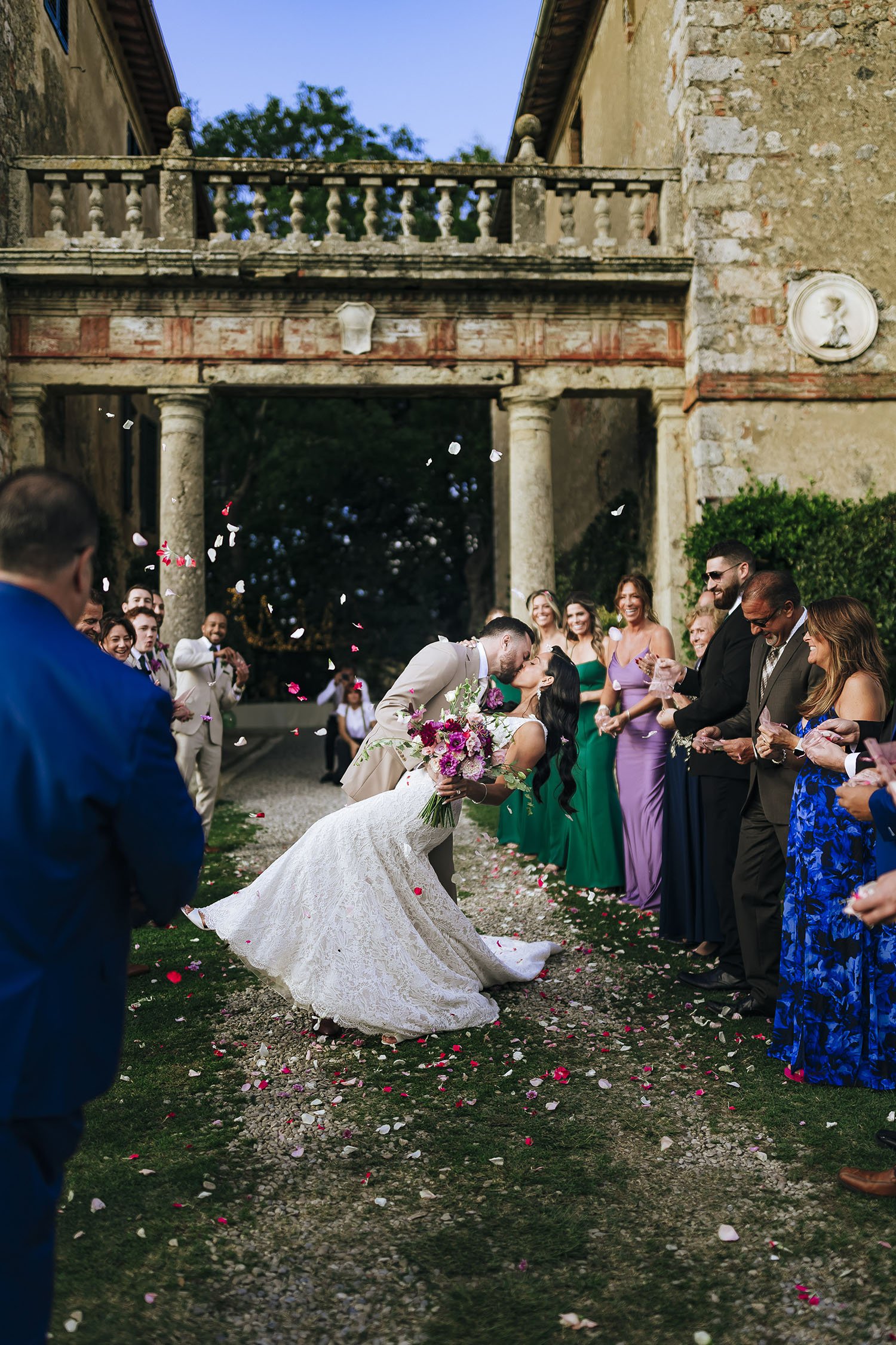 bride and groom kiss celbrated by their guests throwing confetti