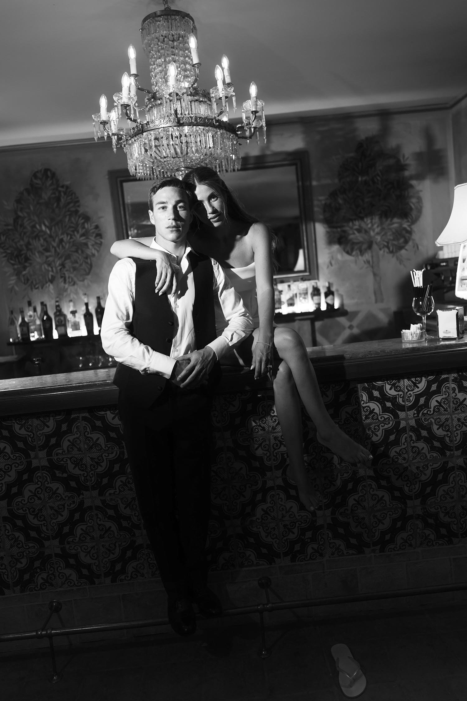 classy portrait of the bride sitting on the bar and holding the groom