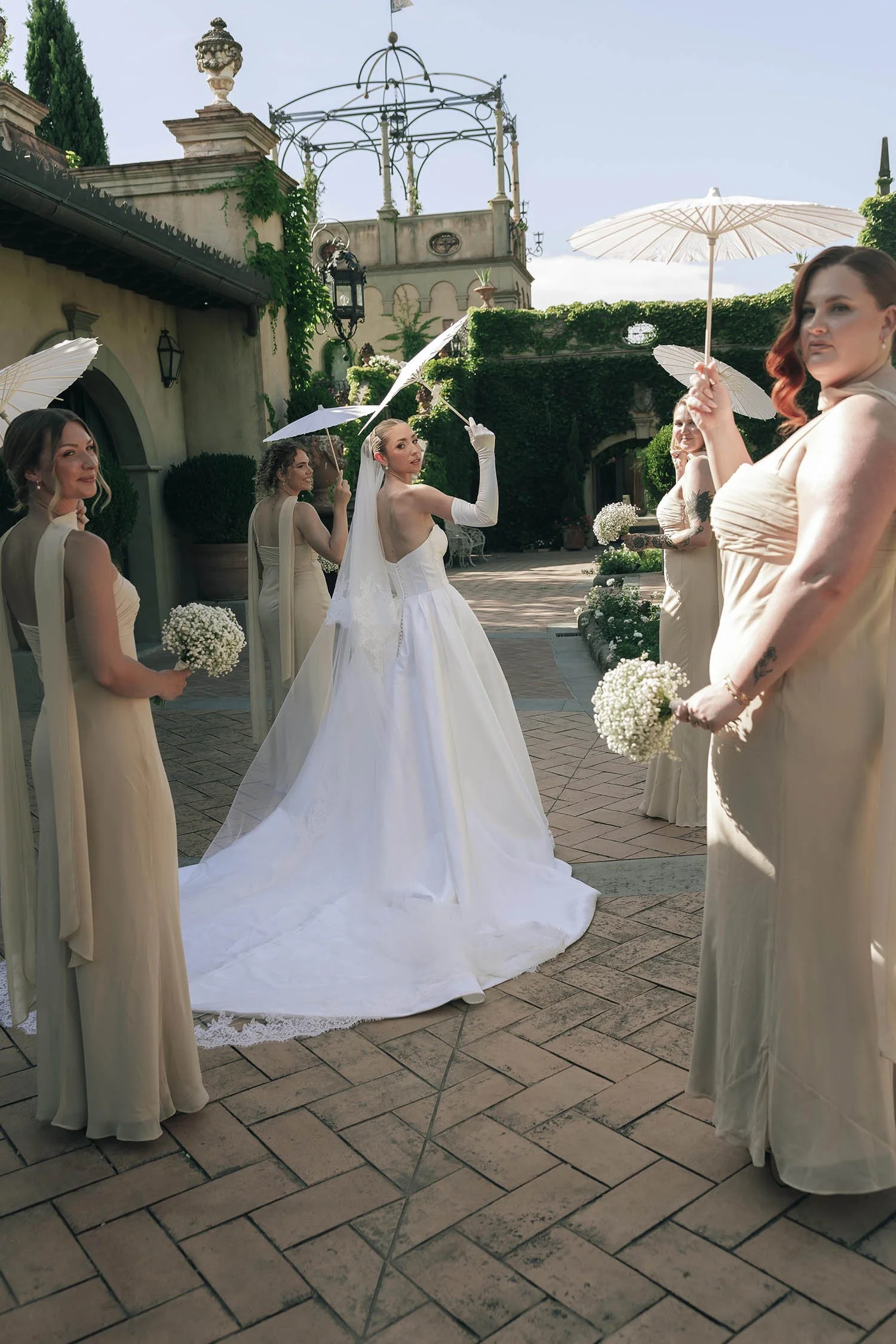 the bride posing with her bridesmaids holding parasoles