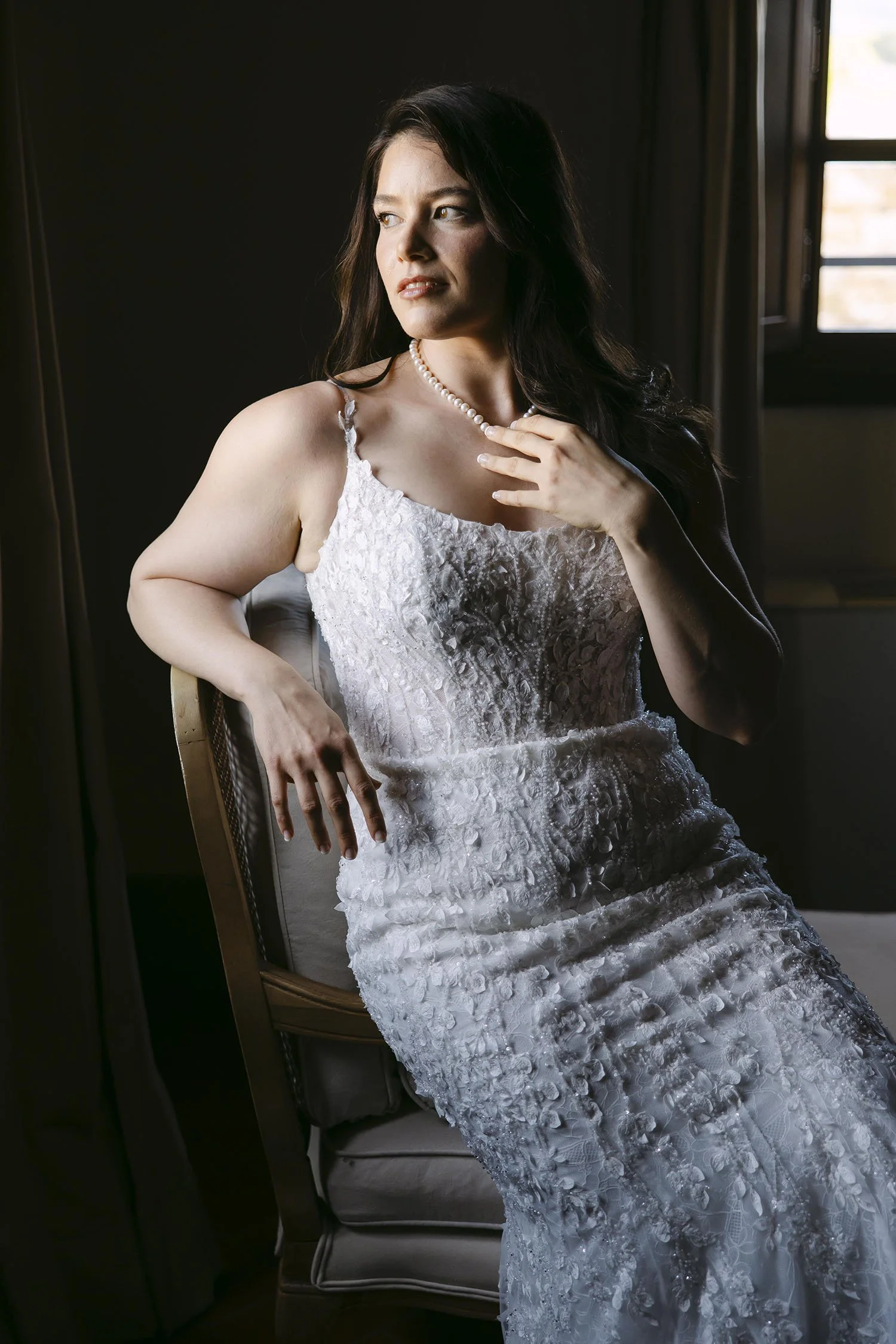 Bride sitting in a dramatic light and looking outside the window