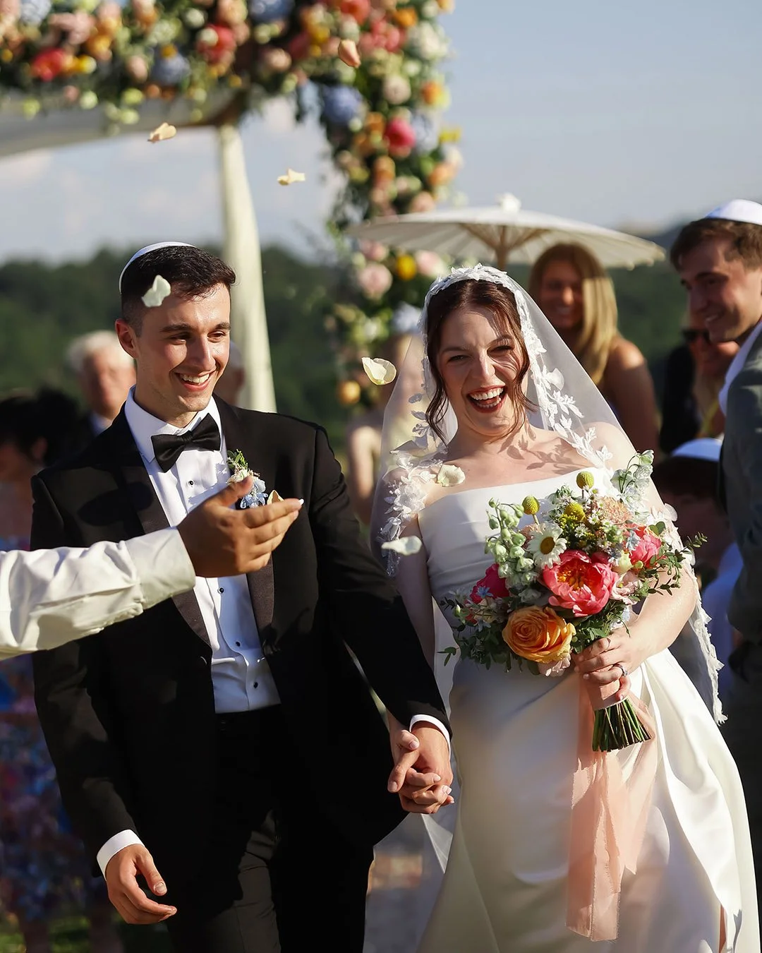 Bride and groom walking down the aisle with guests celebrating them and throwing confetti