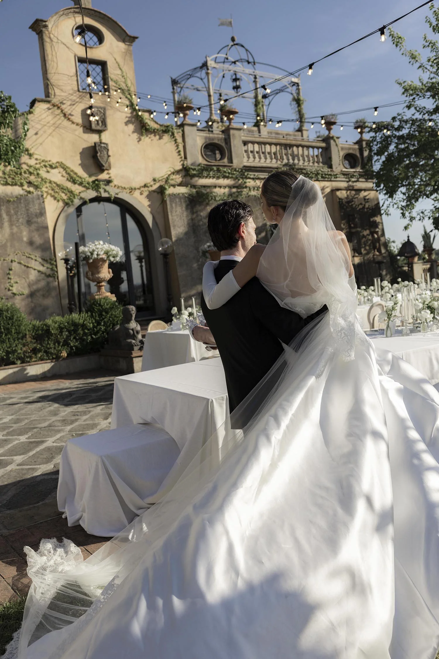 groom holding the bride and walking away from the tables kissing each other