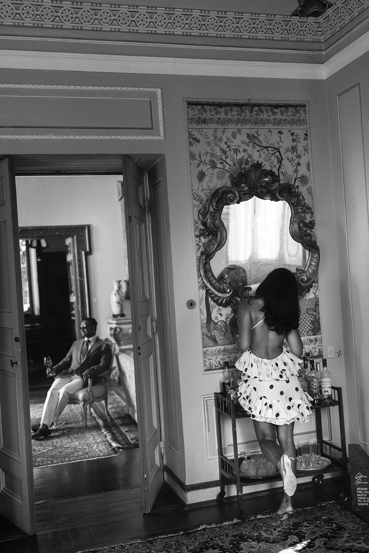 bride looking herself in the mirror while the groom is sitting on an armchair at Torre di Pila