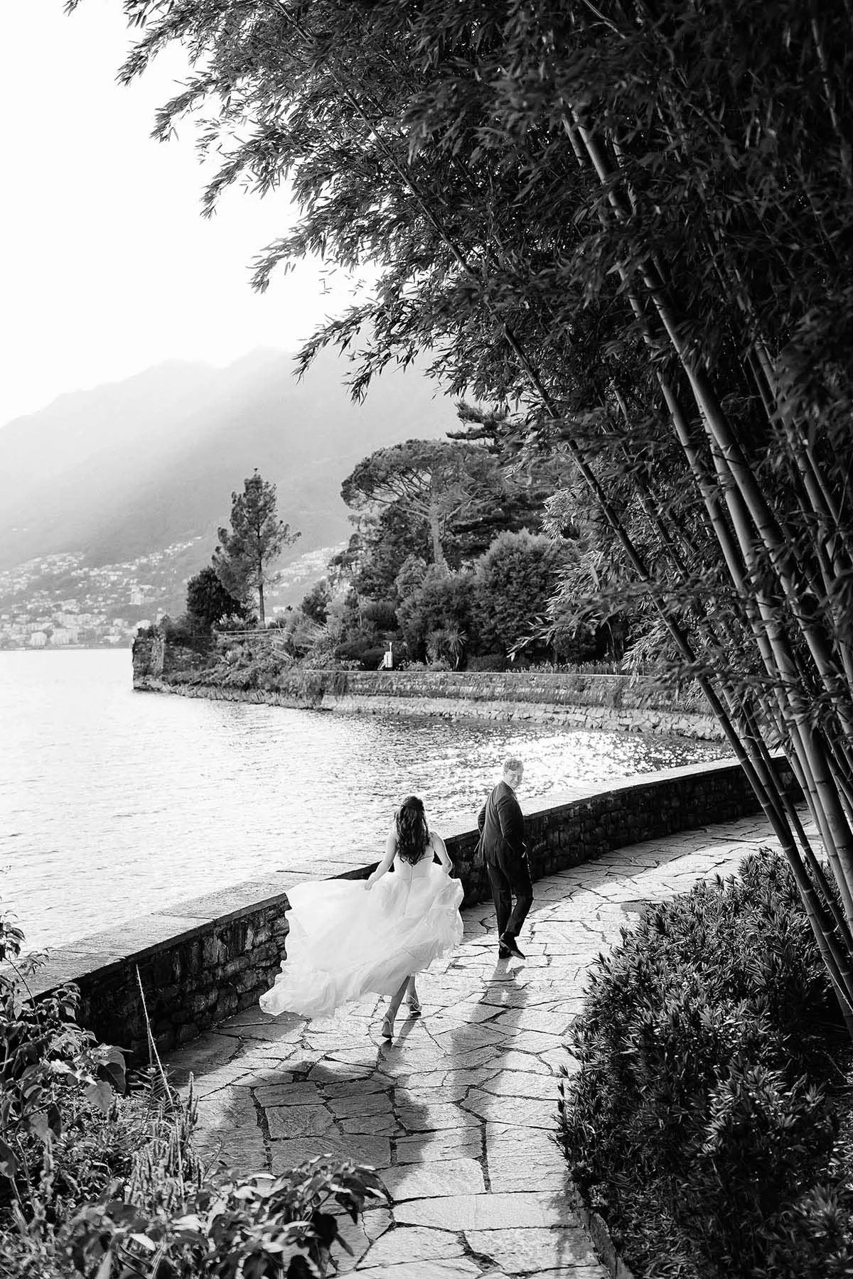 Artistic photo of bride and groom walking together by the lake at Villa Emden in Brissago, destination wedding in Switzerland. Photo by Rellini art studio best wedding photographer in Umbria