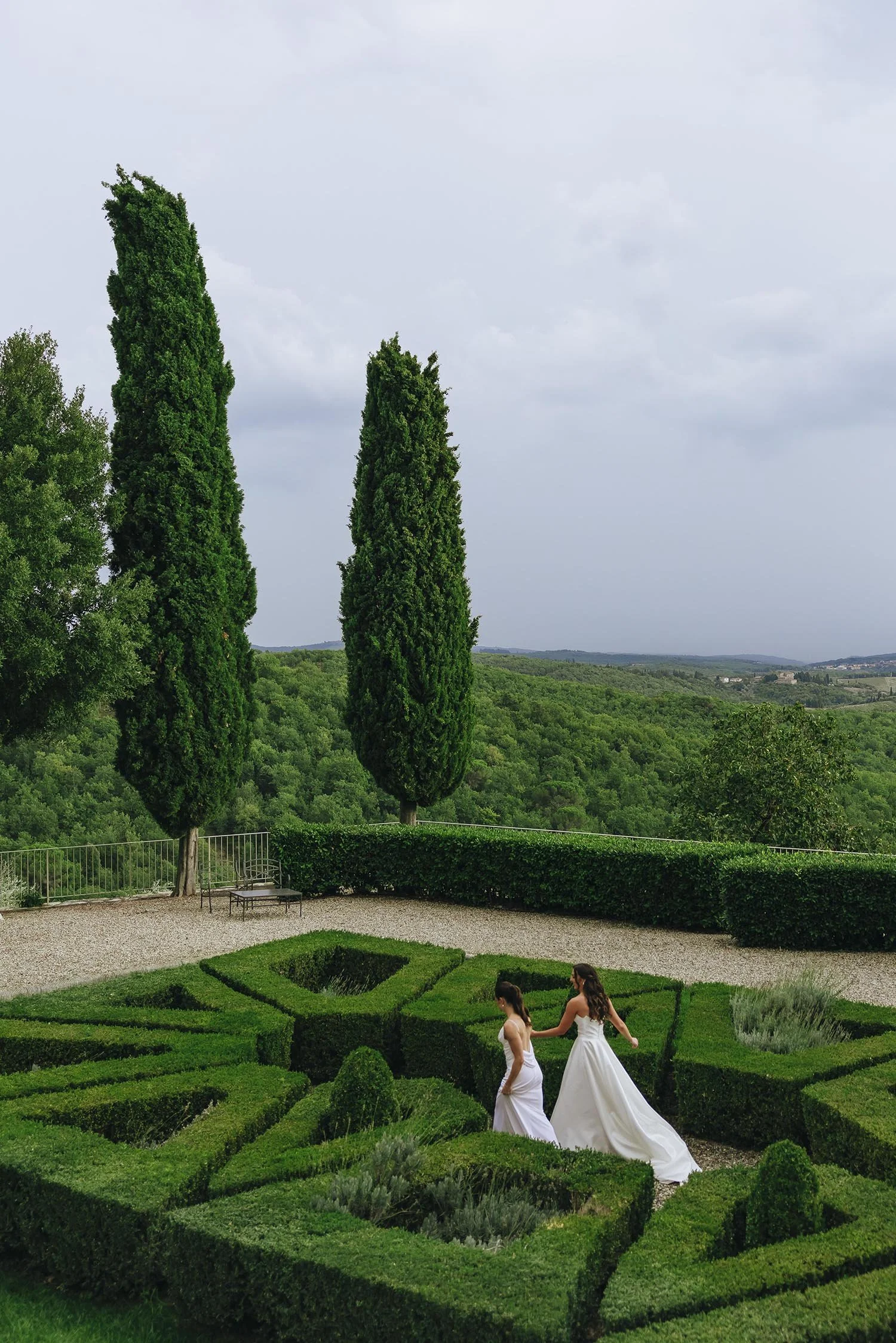 Two brides walking together in the gardens of Castello la Leccia in Tuscany