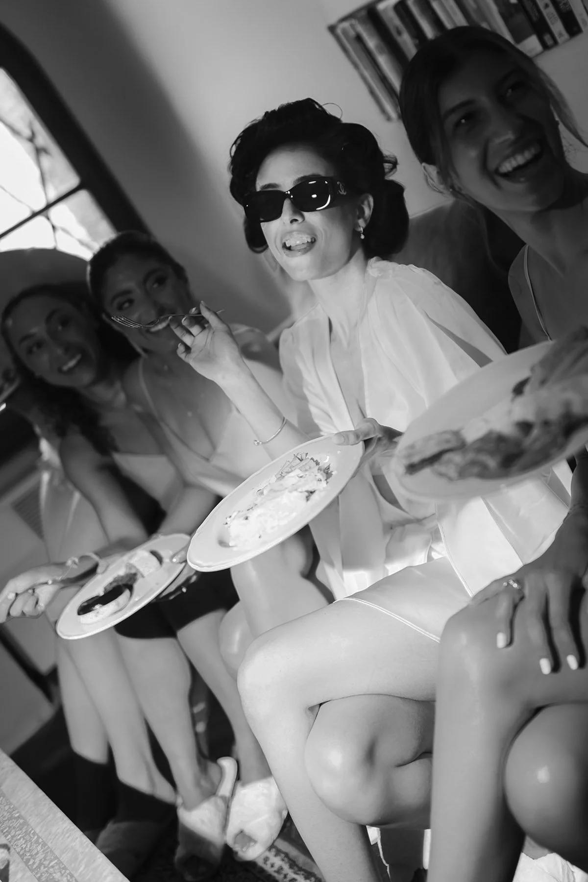 a bride having pasta with her bridesmaids wearing sunglasses with her bridesmaids before getting into their dress