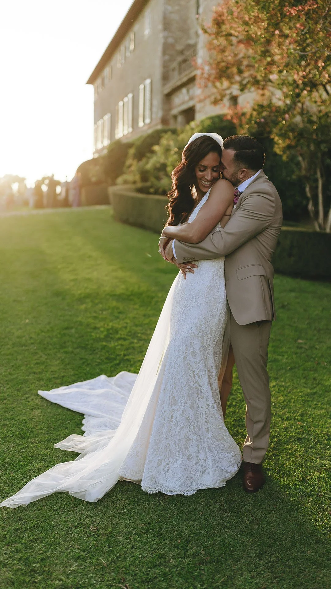 groom holding the bride with the sun setting on the facade of the villa at Borgo Stomennano