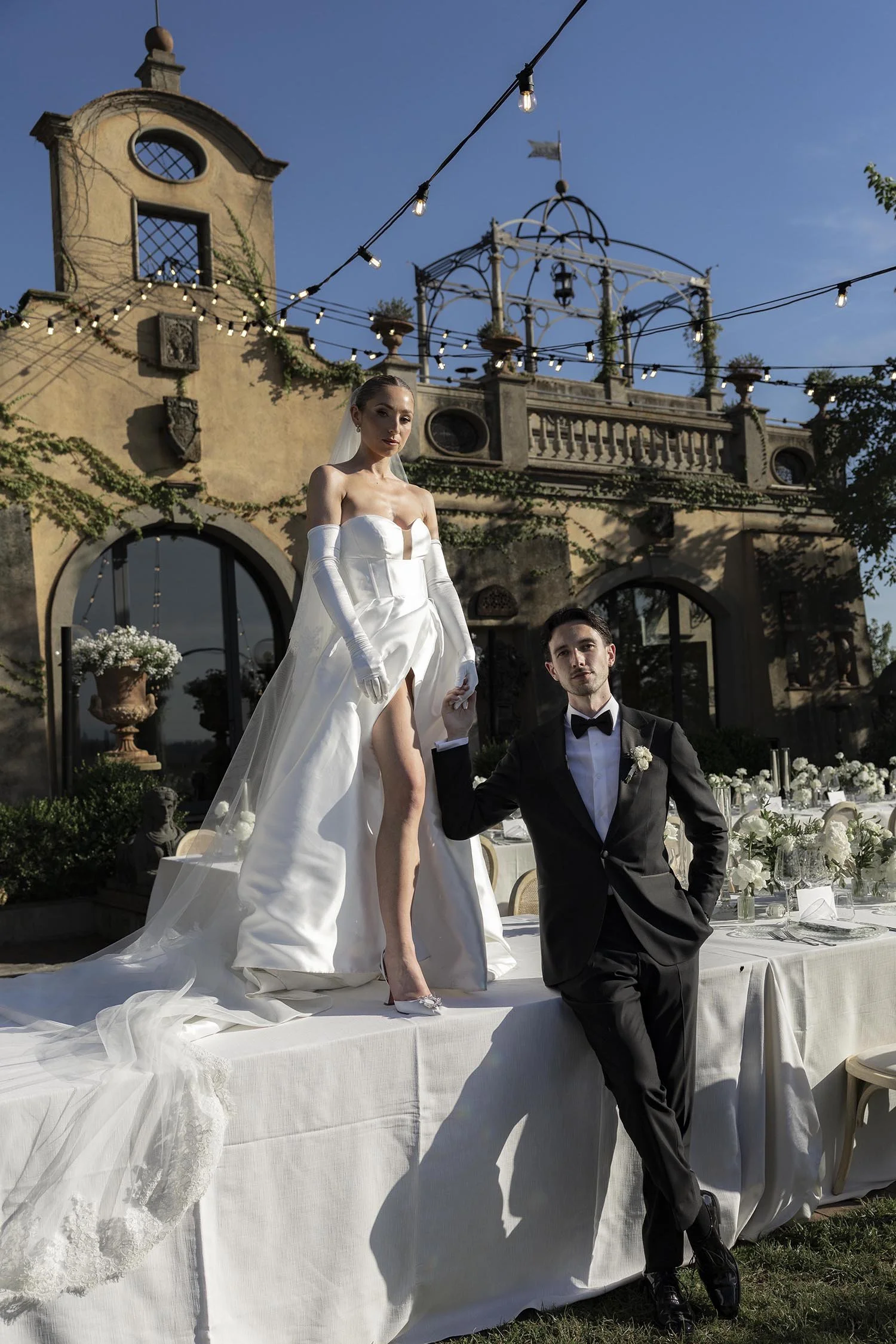 the bride standing on top of the dinner table with the groom holding her hand at Tenuta Corbinaia