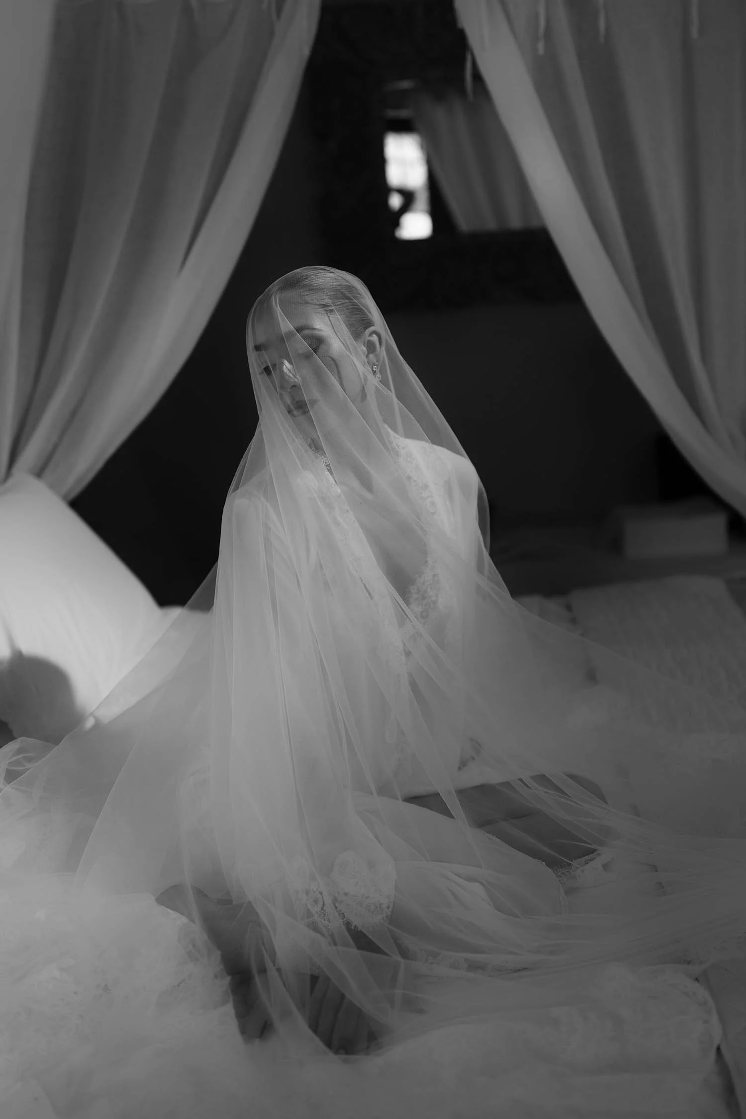 the bride sitting on the bed covered with the veil