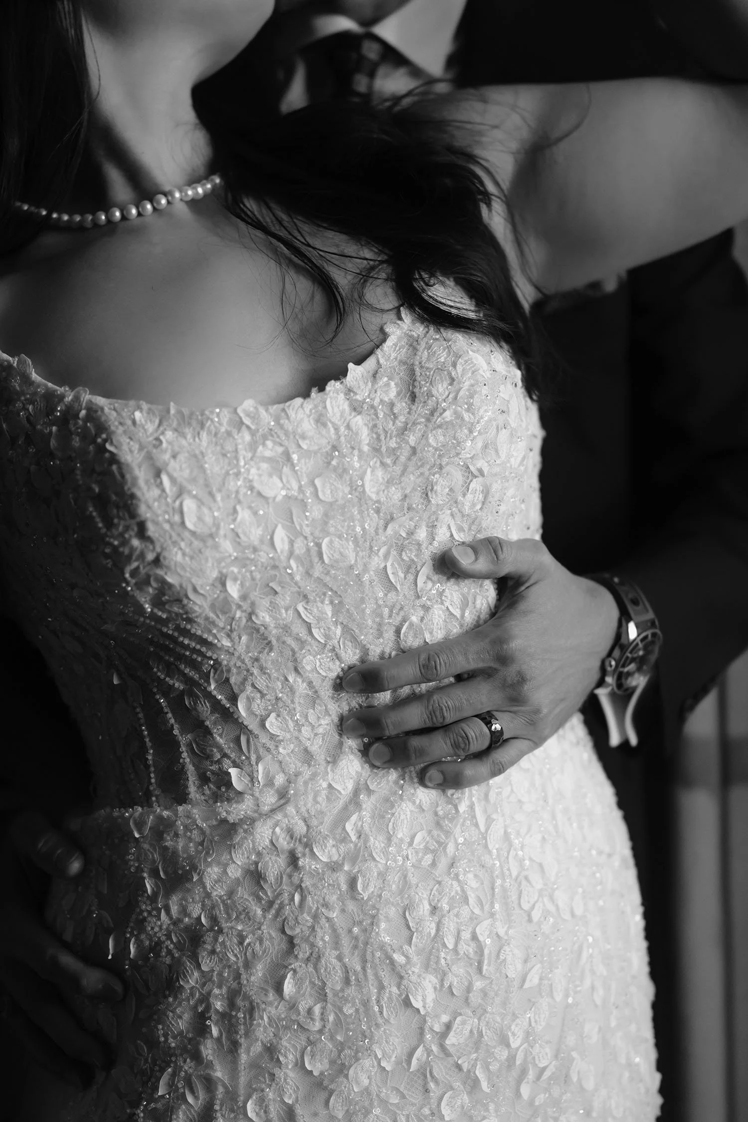Details of the groom holding the bride and kissing