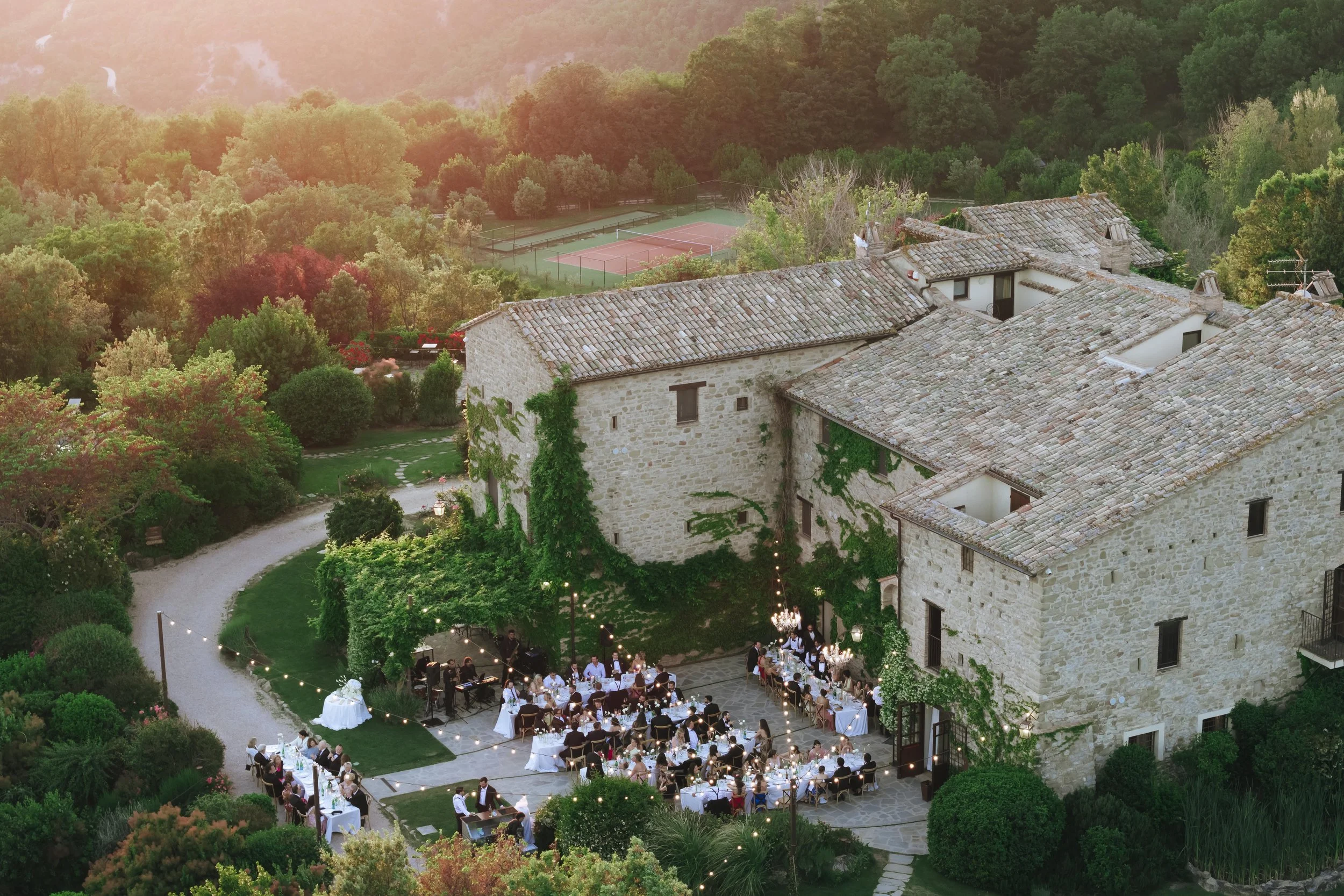 aerial view of Castello di Petrata with guests seated for dinner at sunset