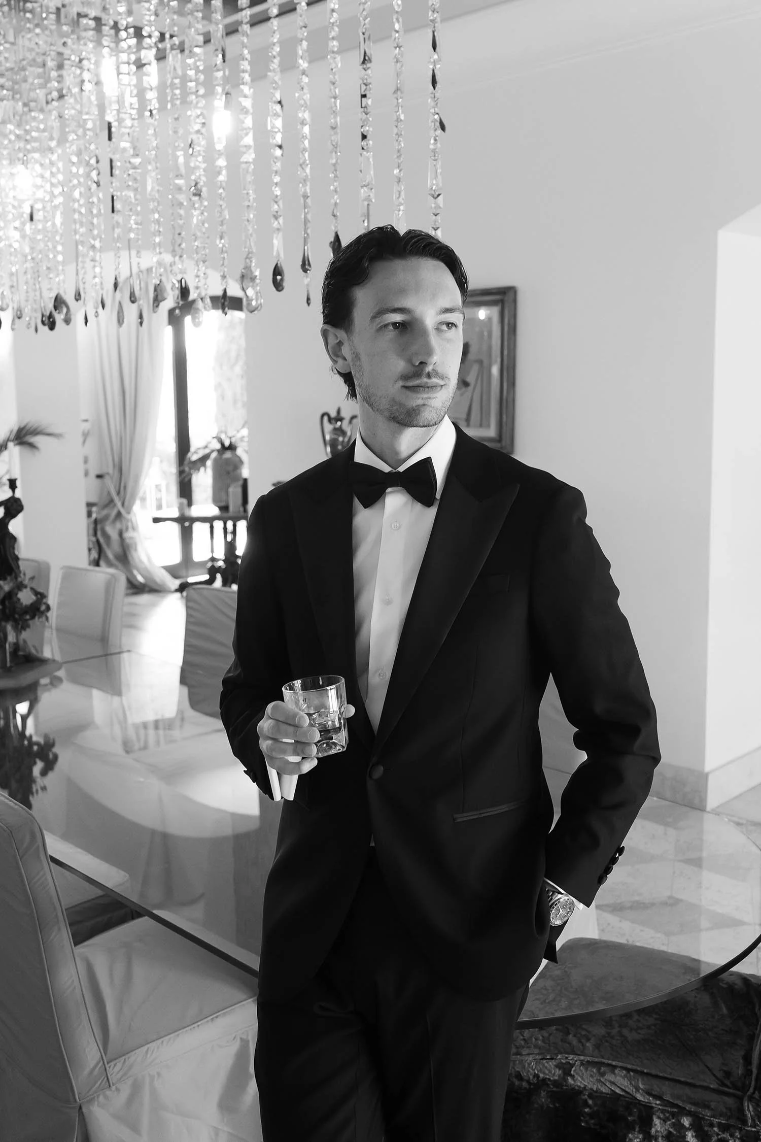 the groom posing by the table with a glass in his hand