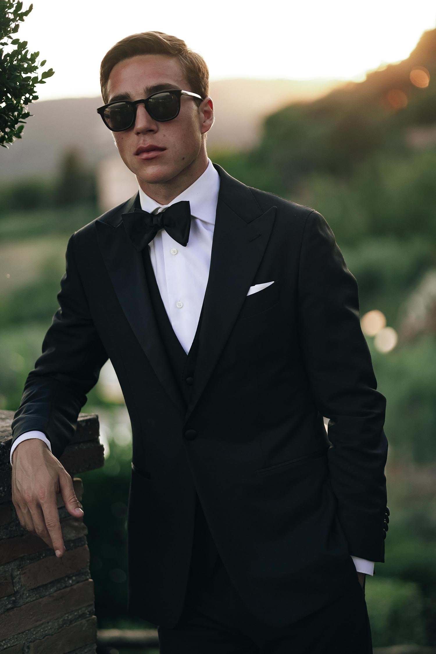 portrait of the groom wearing sunglasses at sunset