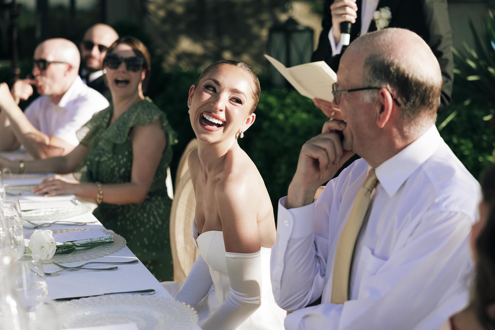 Bride and groom and their guests having fun during the speeches by the tables