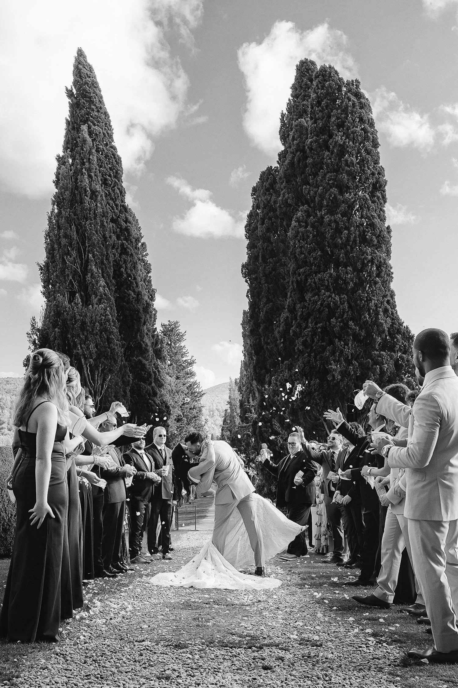 Bride and groom kiss down the aisle with all the guests celebrating them throwing confetti at Borgo Stomennano in Tuscany. photo by Rellini art studio 