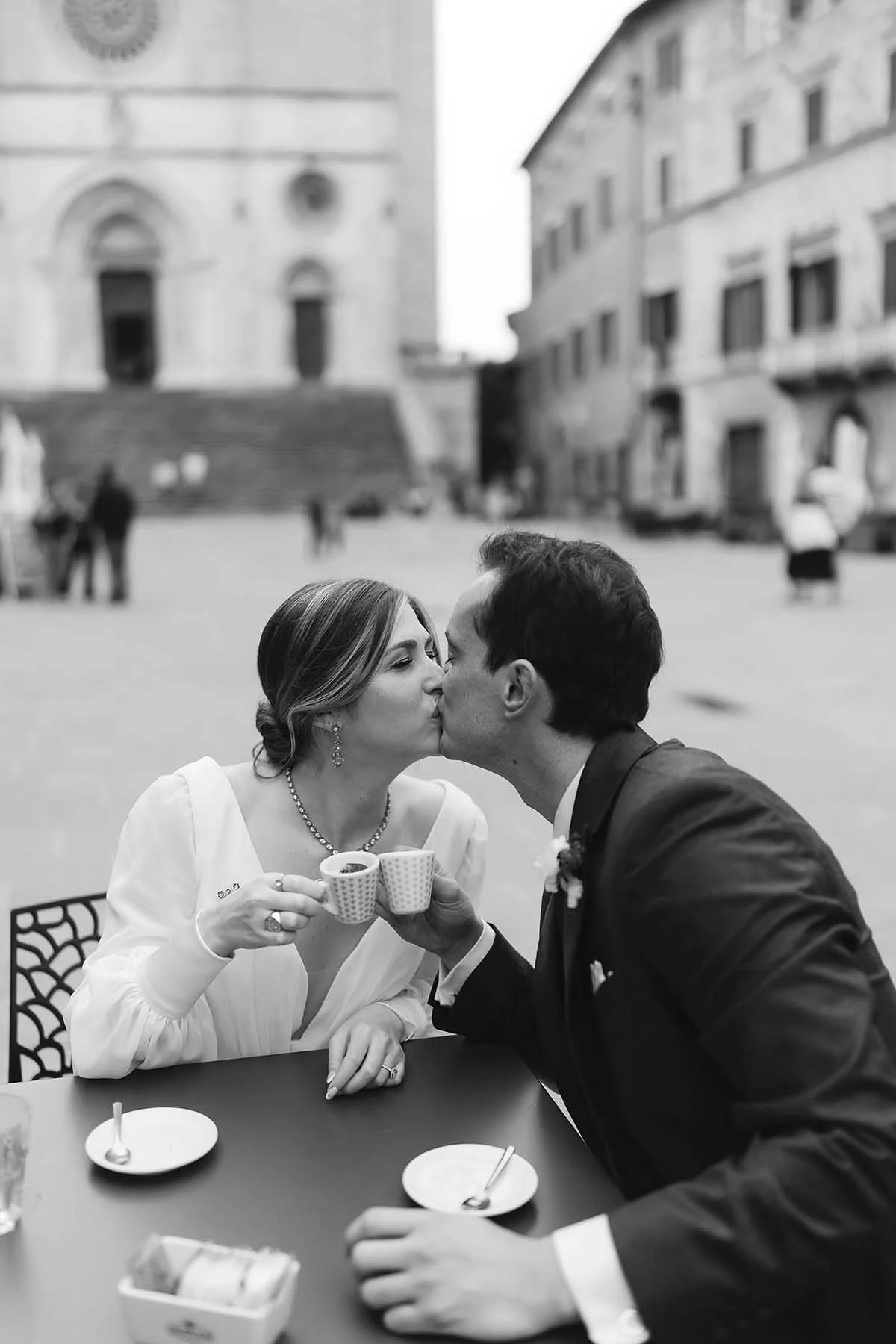 Documentary and editorial photo by Rellini art studio, best wedding photographers in Umbria and Tuscany, couple kissing while having italian coffee in Todi square in Umbria