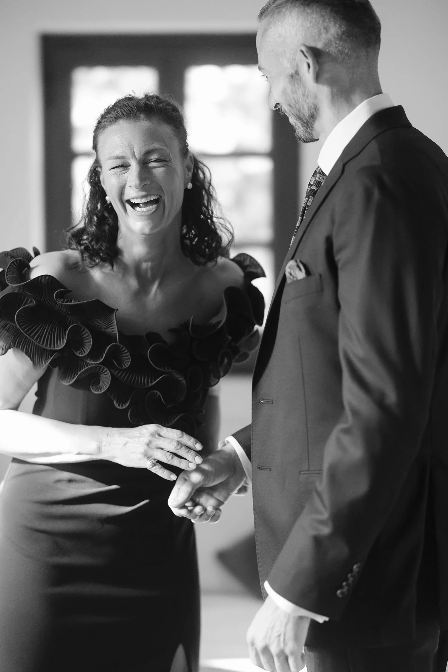 The sister of the groom helping him to get dressed and laughing