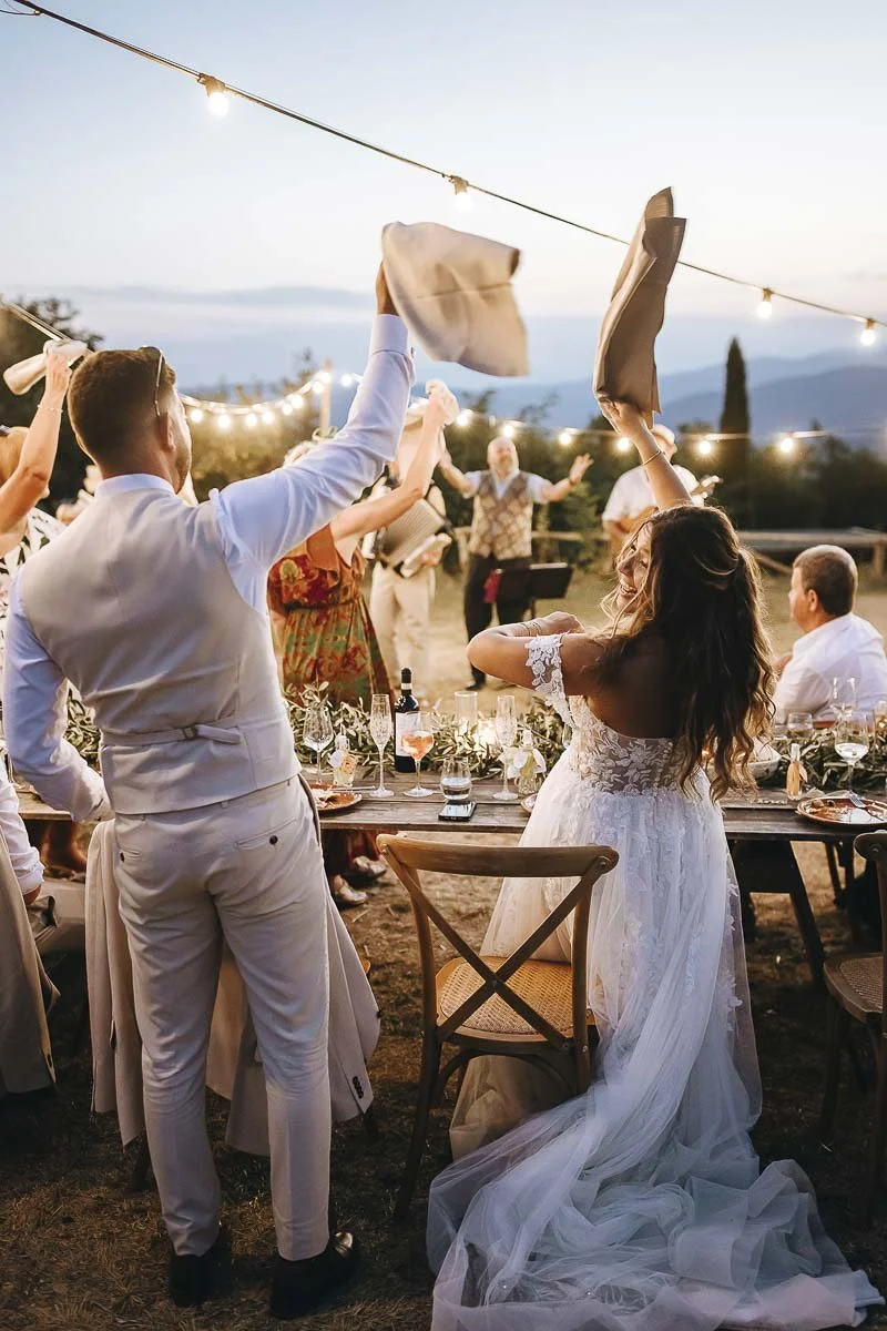 Destination wedding at Ristonchi castle near Florence in Tuscany. bride and groom celebrate and dance by the table during the dinner 