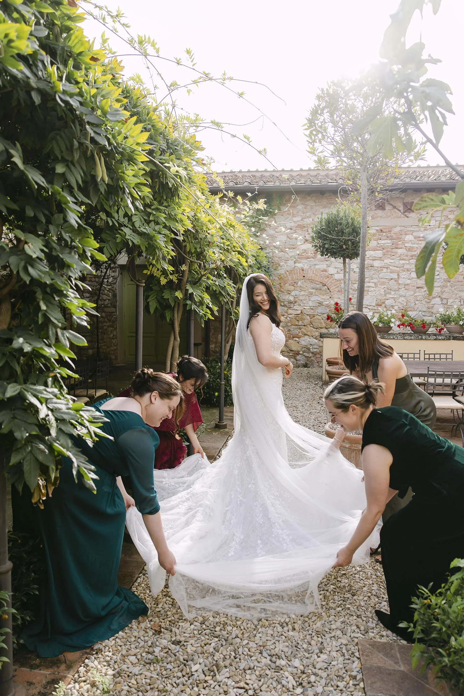 The friends help the bride placing the dress on the floor