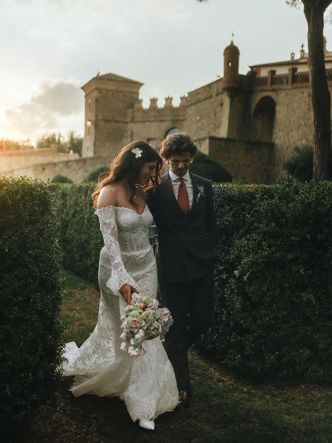 bride and groom walk together at sunset with the stunning Castello di Solfagnano in the background, photo by Rellini art studio