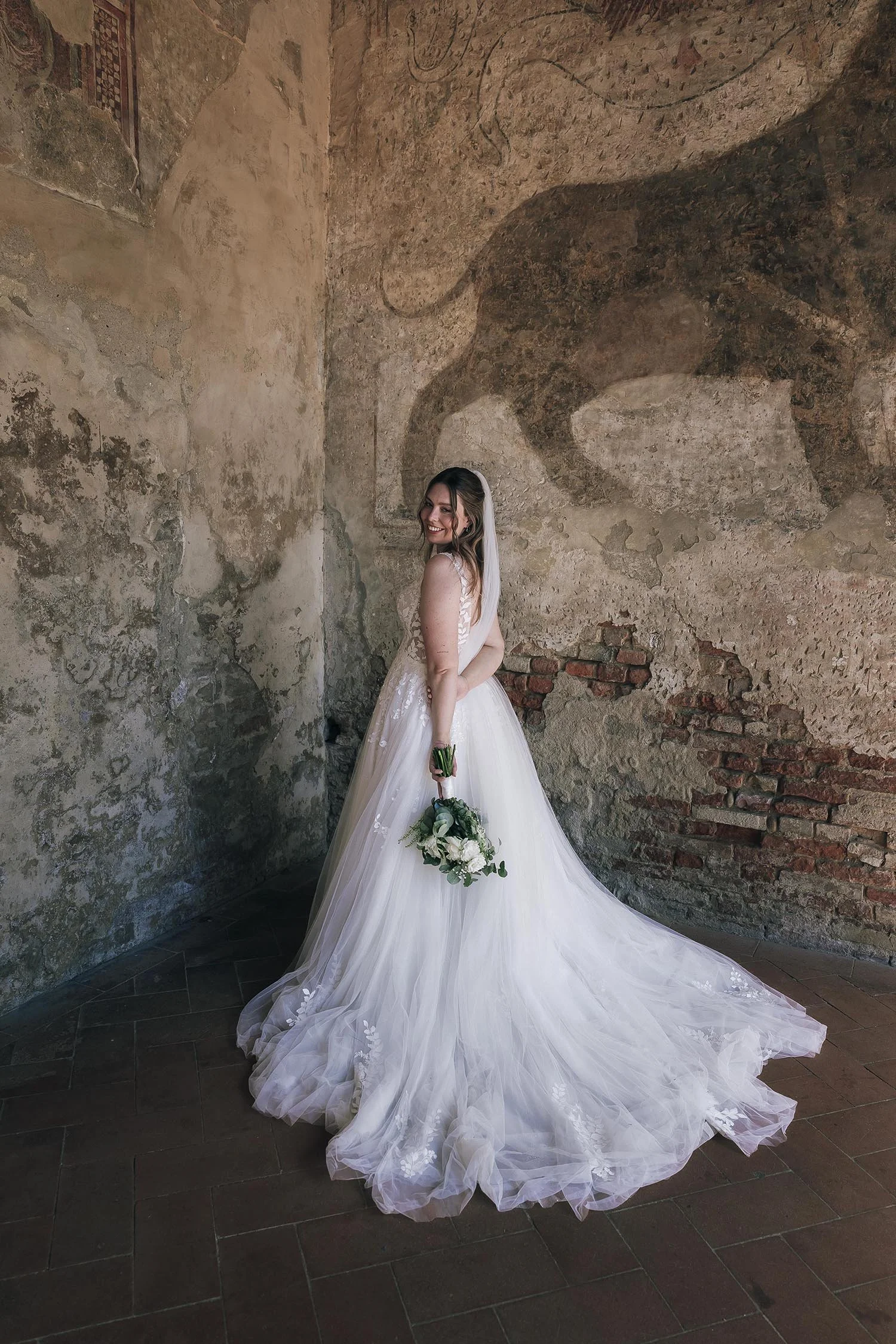 Classy portrait of the bride posing in her dress under an ancient building in Certaldo, Tuscany