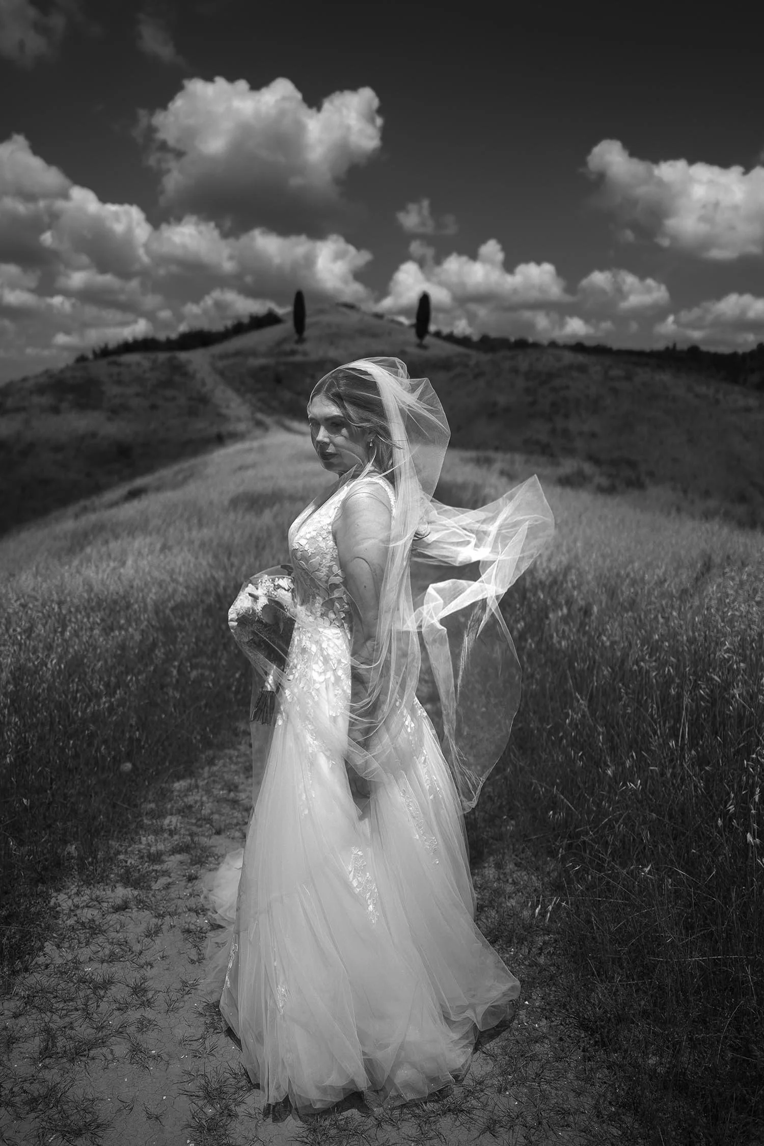 Timeless portrait of the bride posing under the veil on a typical tuscan hill