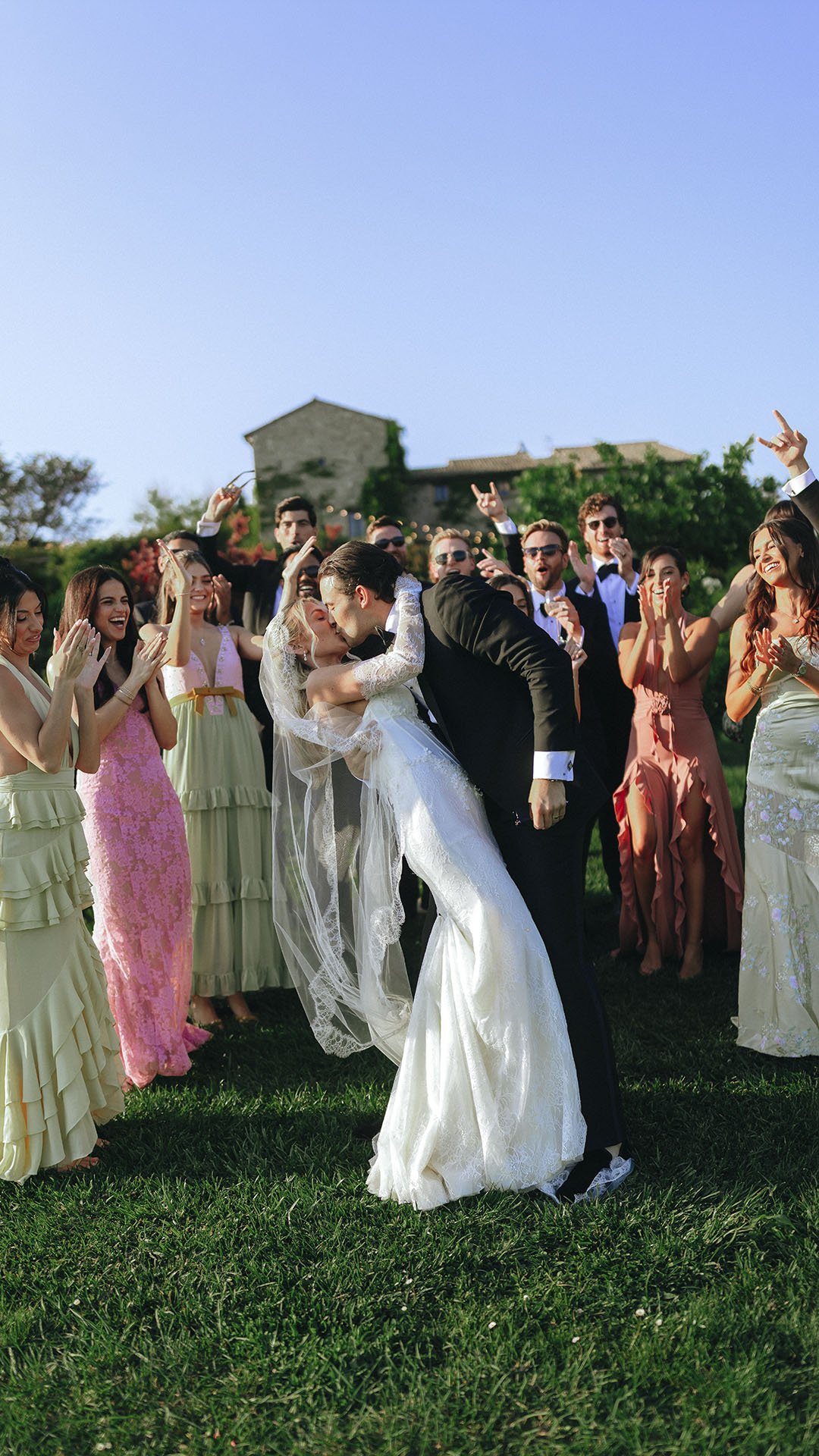 bride and groom kiss each other with their friends celebrating in the background at Castello di Petrata