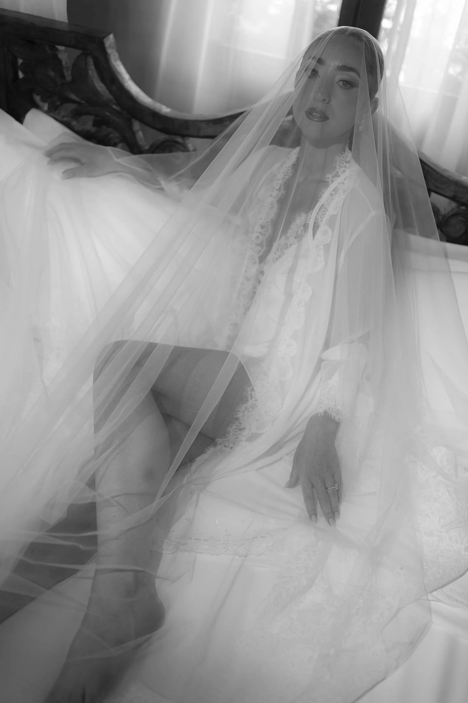 the bride in her underwear covered by the veil and laying down on the bed
