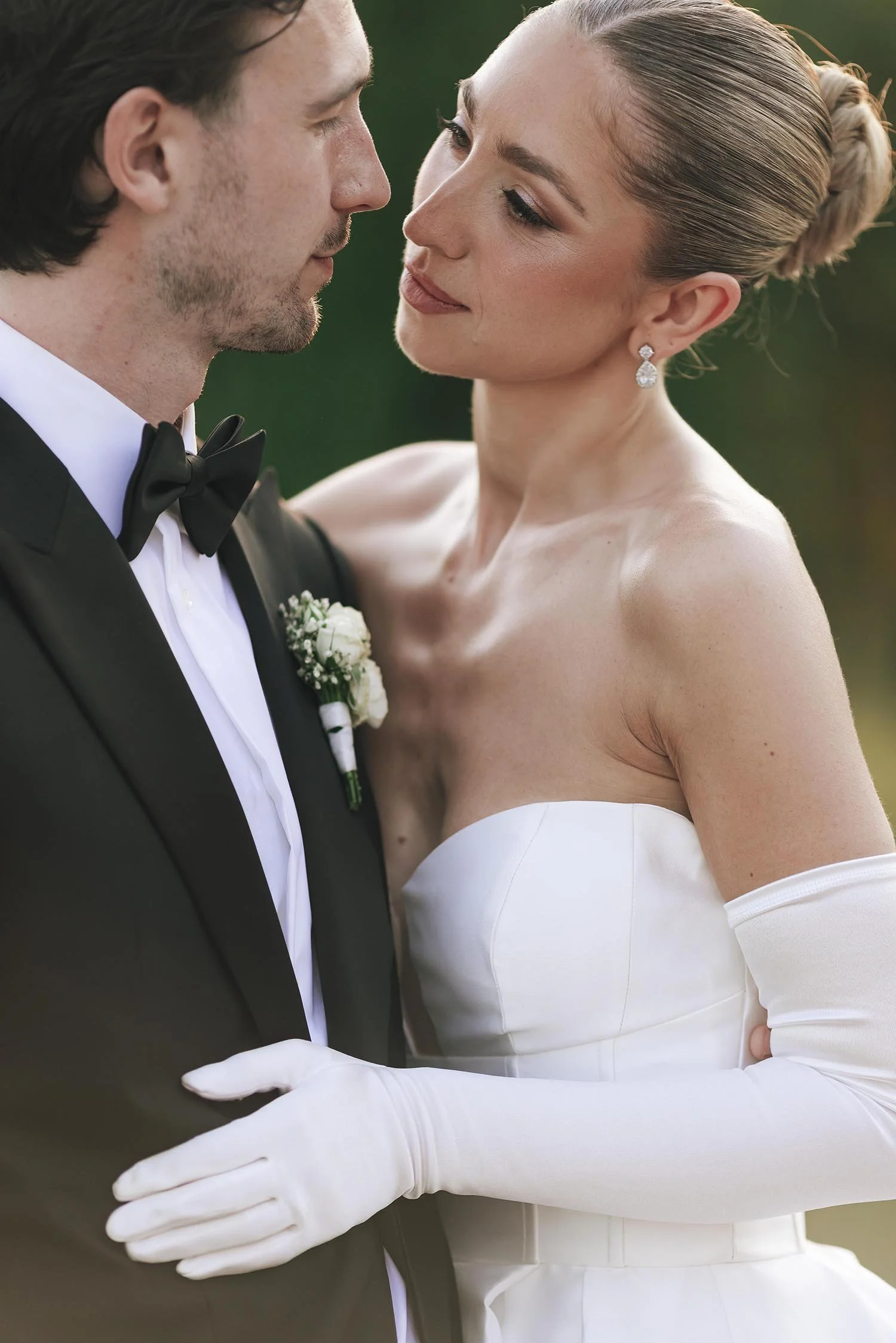 Bride and groom kiss each other in the doorway between the cypresses at sunset