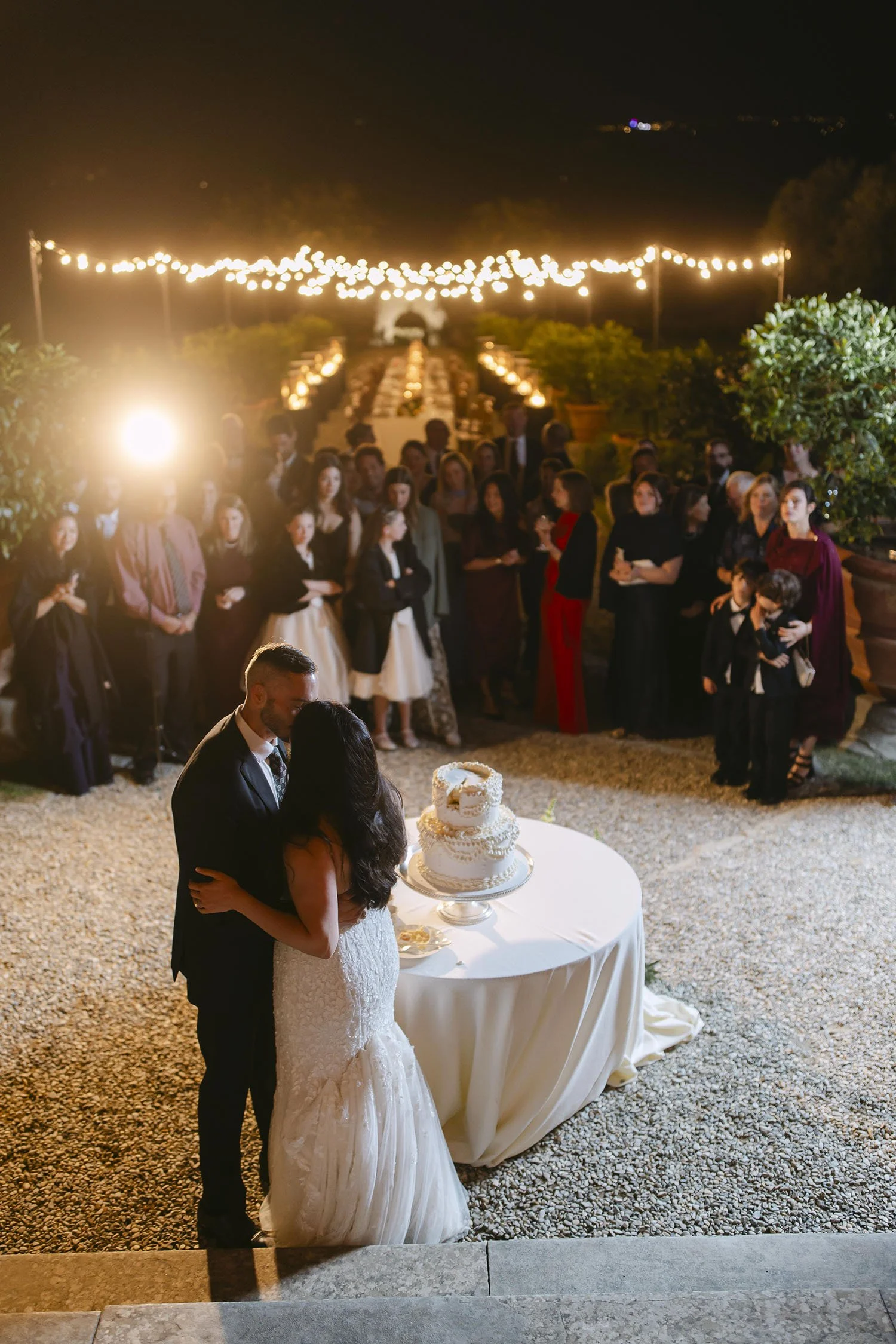 Bride and groom kiss each other in front of their guests by night