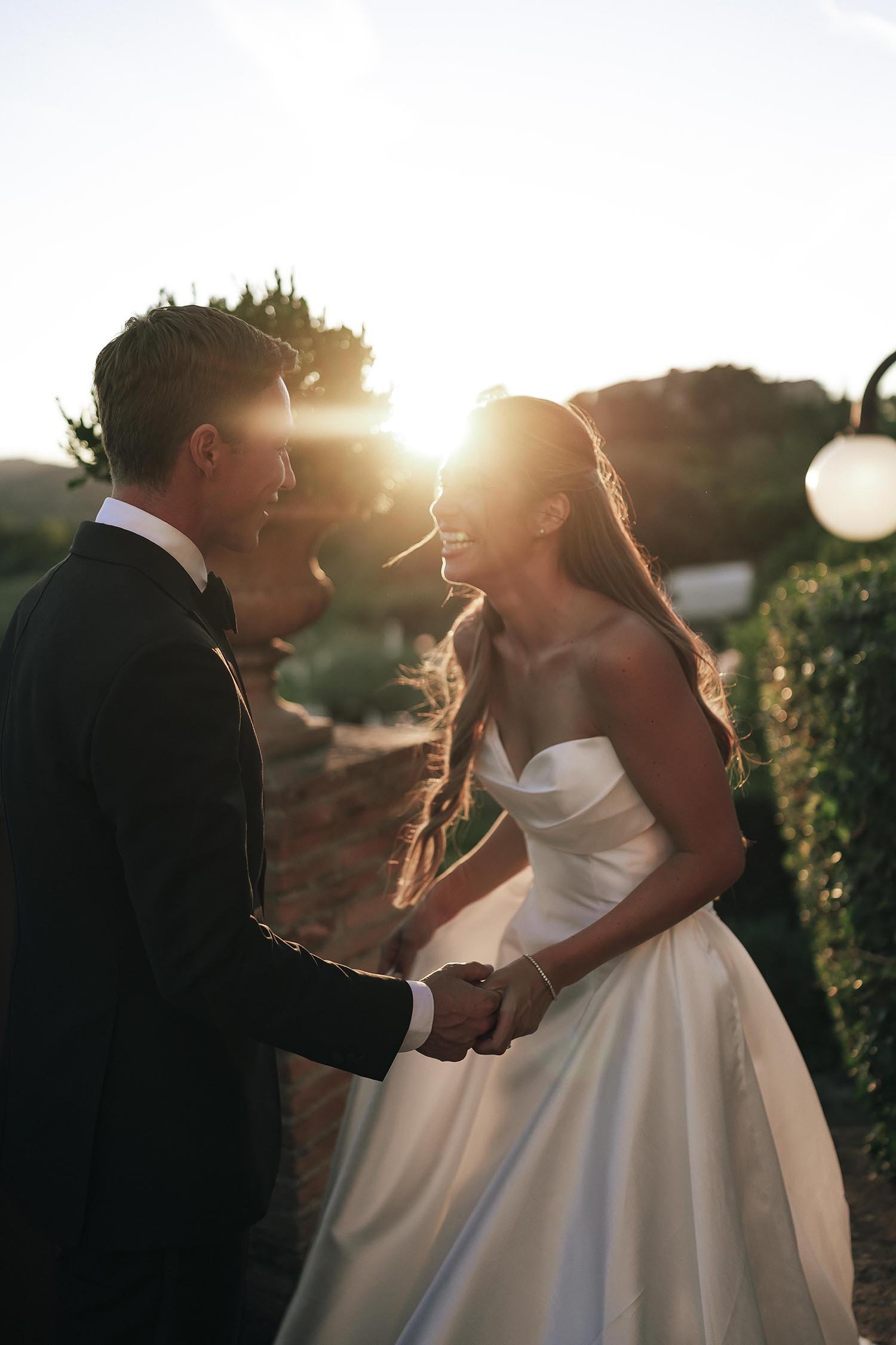bride and groom laughing wit the sun setting behind them