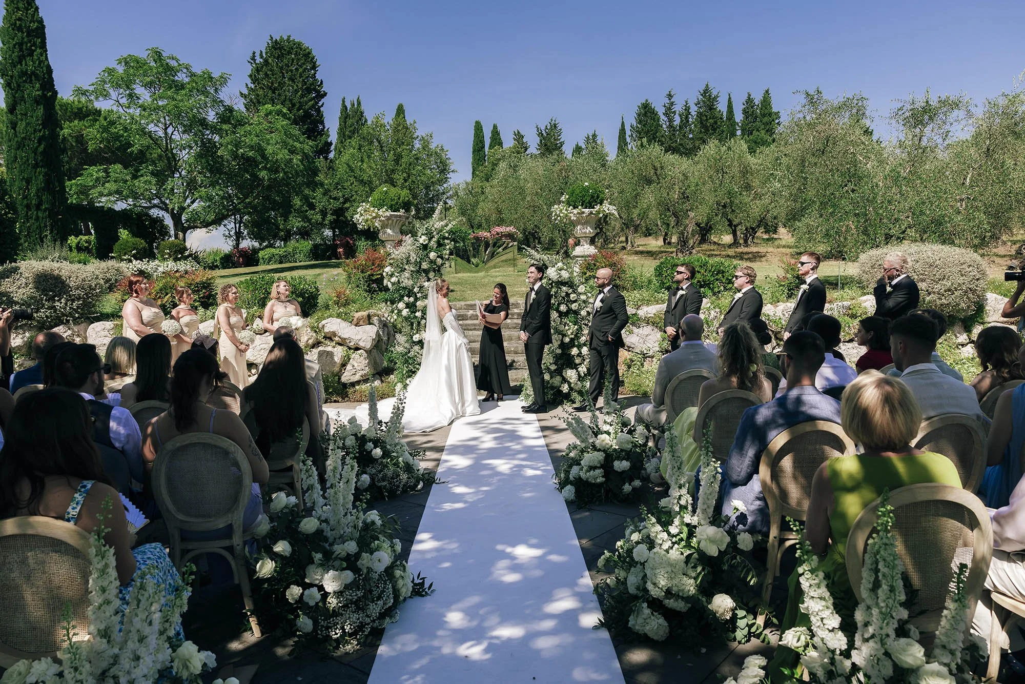 Bride and groom facing each other during the cermeony with all the guests seated in the shade