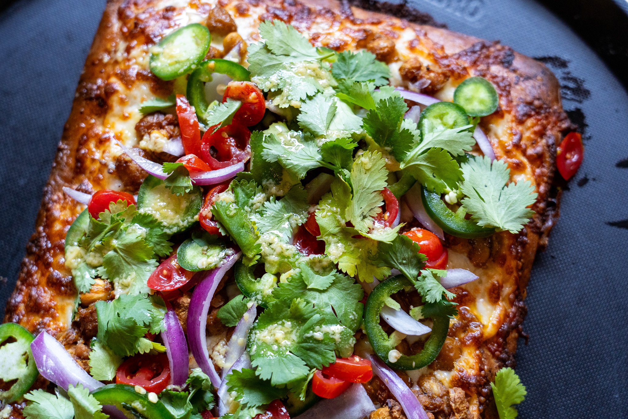 Shiro Wat: Garlic oil, mozz, berbere spiced chickpeas, onion, tomato, jalapeño, cilantro, lemon garlic oil drizzle.