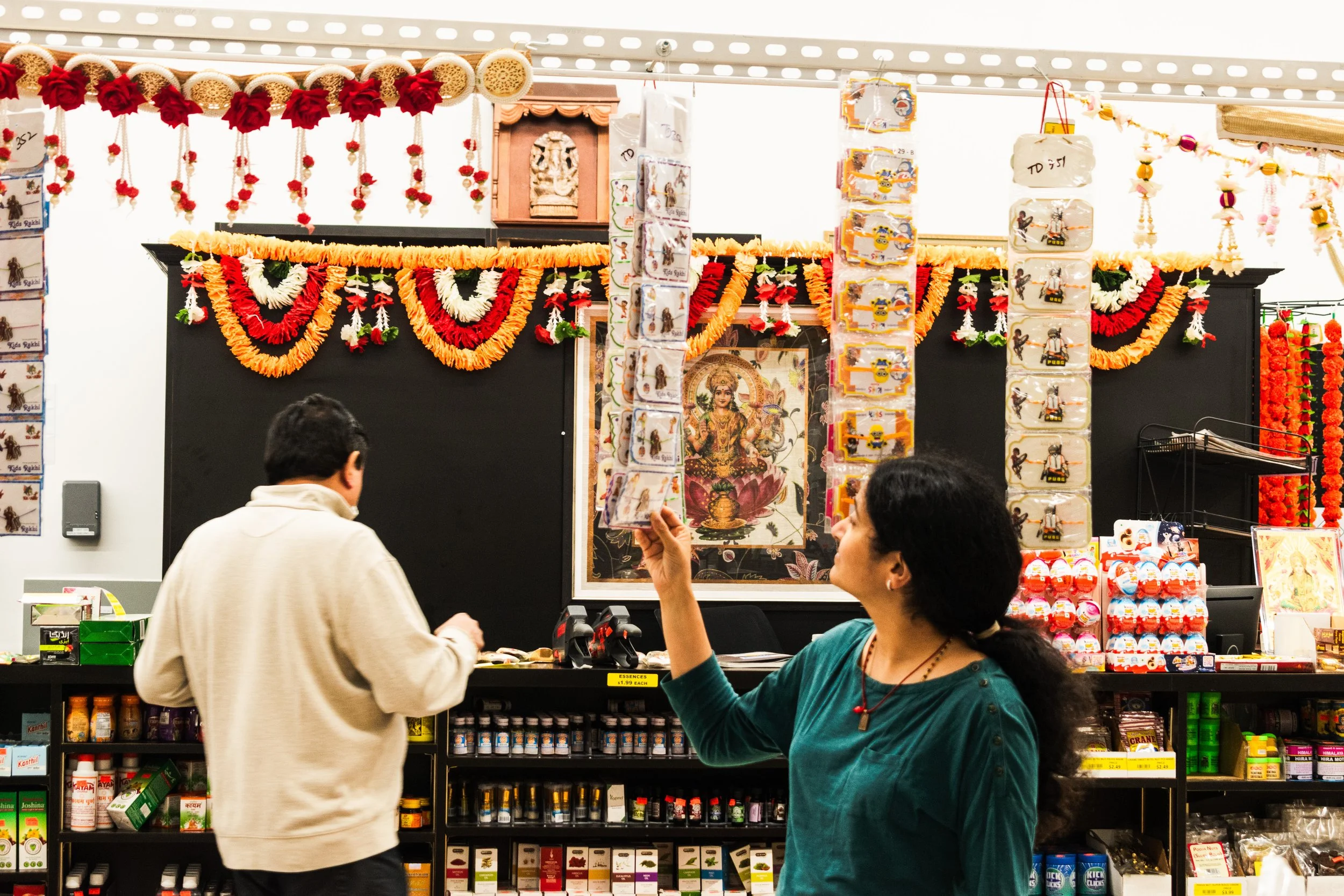 In this photo the lady is trying to pull the Rakhi’s for the festival and the garlands. The man standing behind her is the owner of  the Patel brothers. Indians every day when they are coming to their shops or stores in the morning time, they pray an