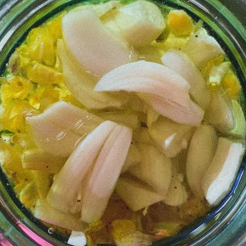 A jar filled with chopped bananas and pineapple chunks.