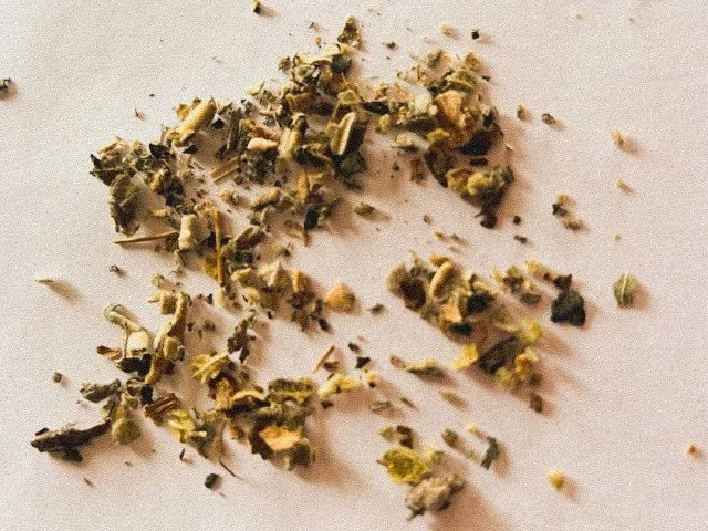 Dried and crushed herbs or plant material on a white surface.