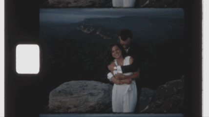 A couple embracing on a mountainside during sunrise on Super 8 film.