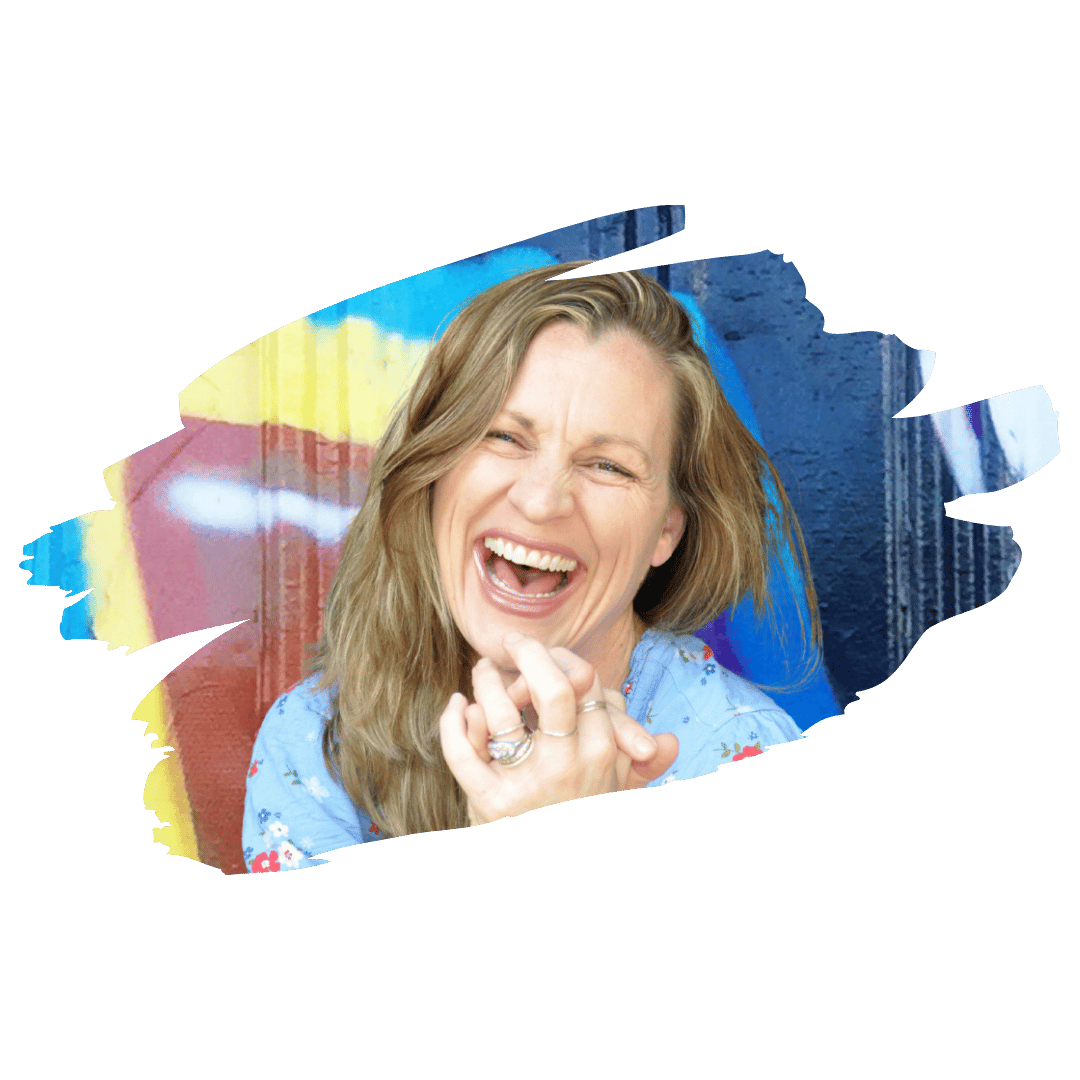 [Image] White adult woman laughing clutching her hands in front of an urban art wall, offering stress management therapy for tweens, teens, and young adults in Denver, Colorado