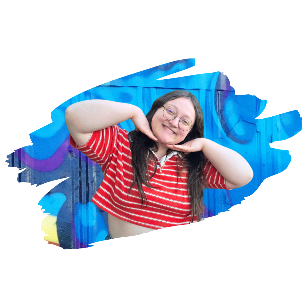 [Image] Latinx non-binary person smiling with hands under chin in front of graffiti art mural; Courtney Romero Teen and Young Adult Therapist at Interfaith Bridge Counseling in Denver, CO